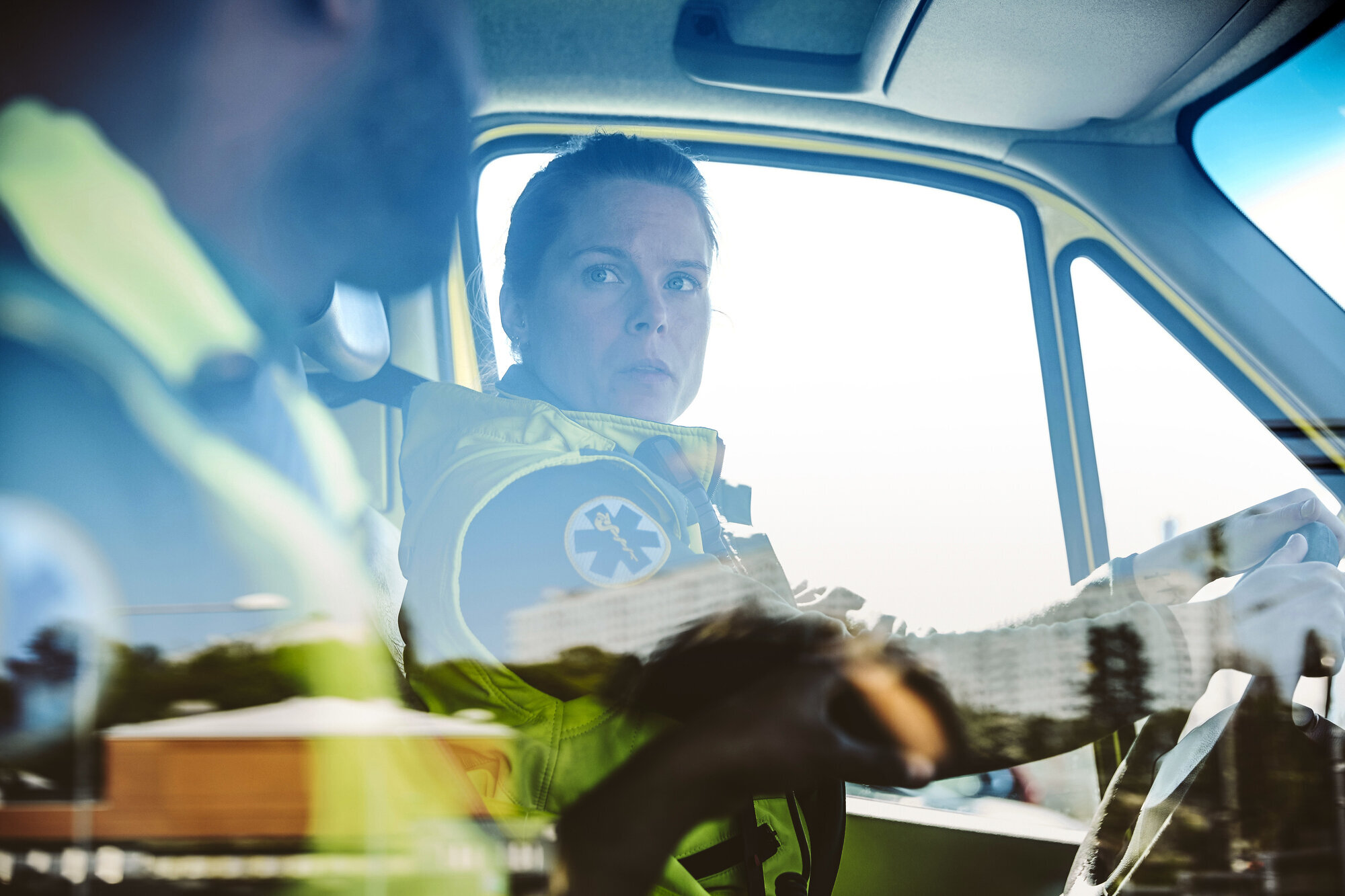 Bildet viser to ambulansearbeidere som sitter i en bil