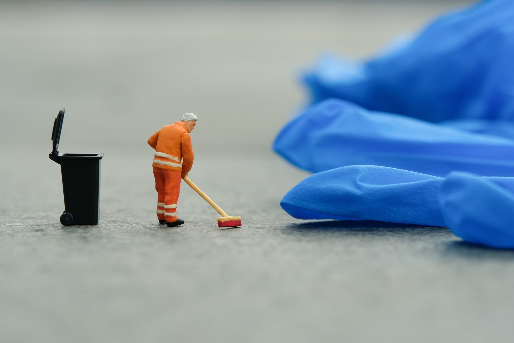 Bildet viser en miniatyrmann som koster opp rundt en engangshanske av plast