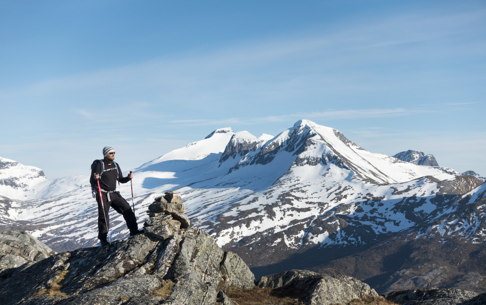 Bildet viser en mannlig turgåer som står på en fjelltopp