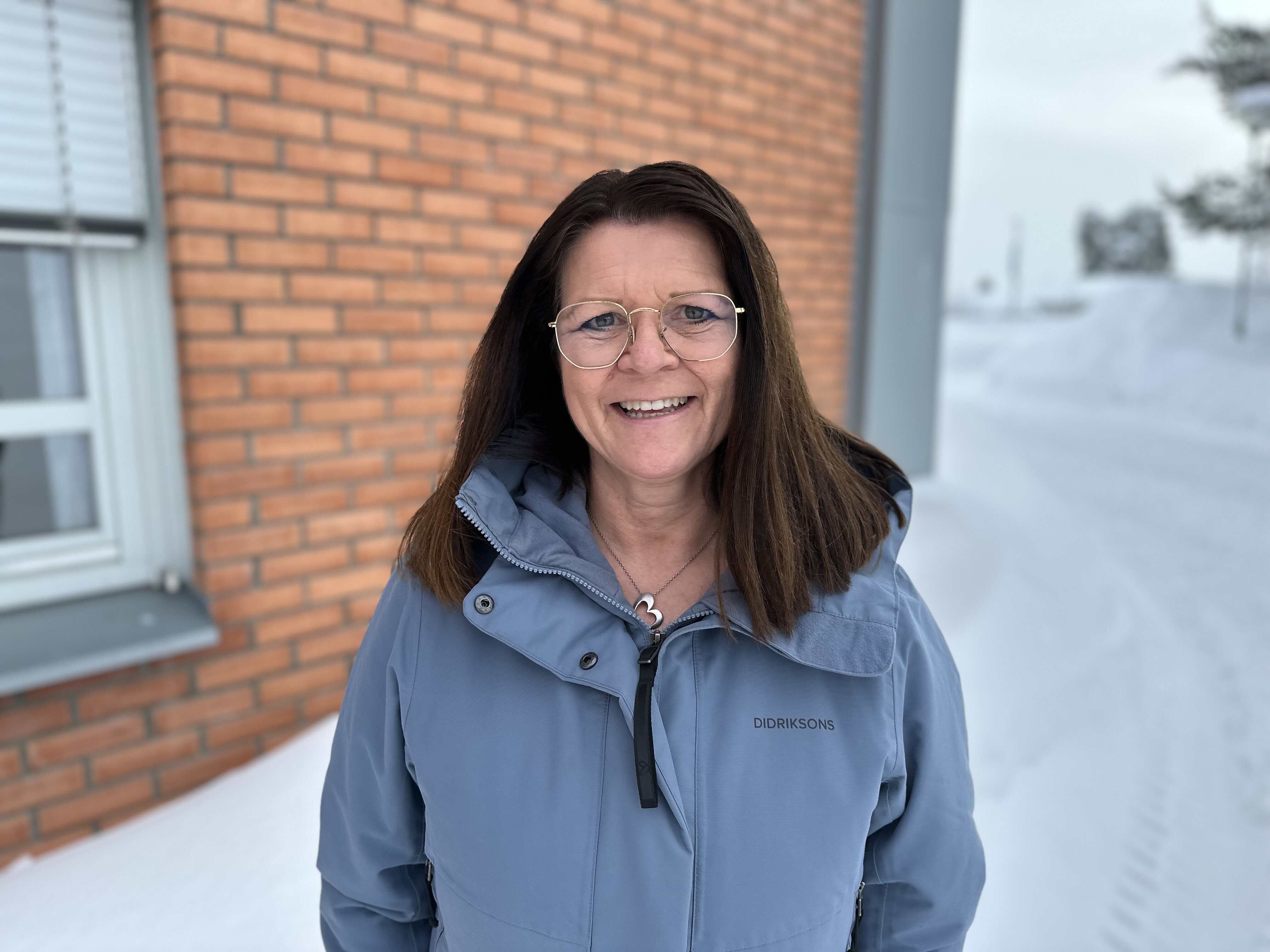 Bildet viser Torhild Sørum. Det er vinter. Hun har på seg en blå jakke og hun smiler til kameraet.