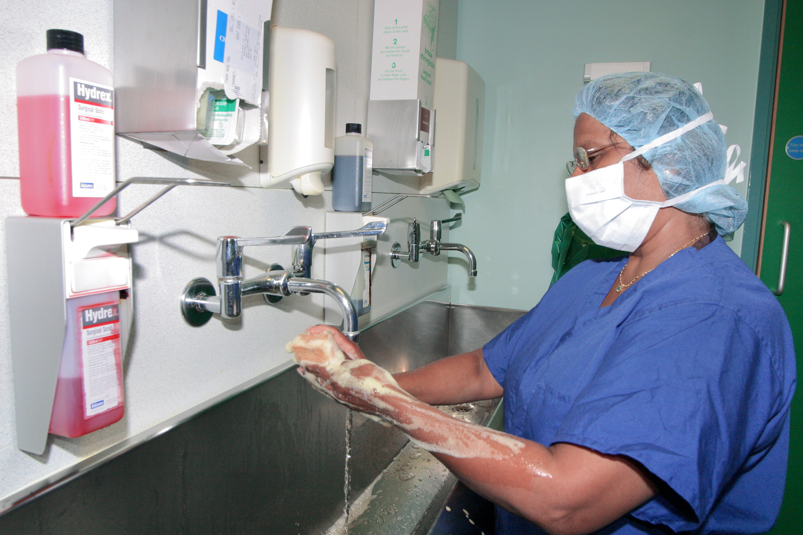 The photo shows a surgical nurse washing her hands before surgery