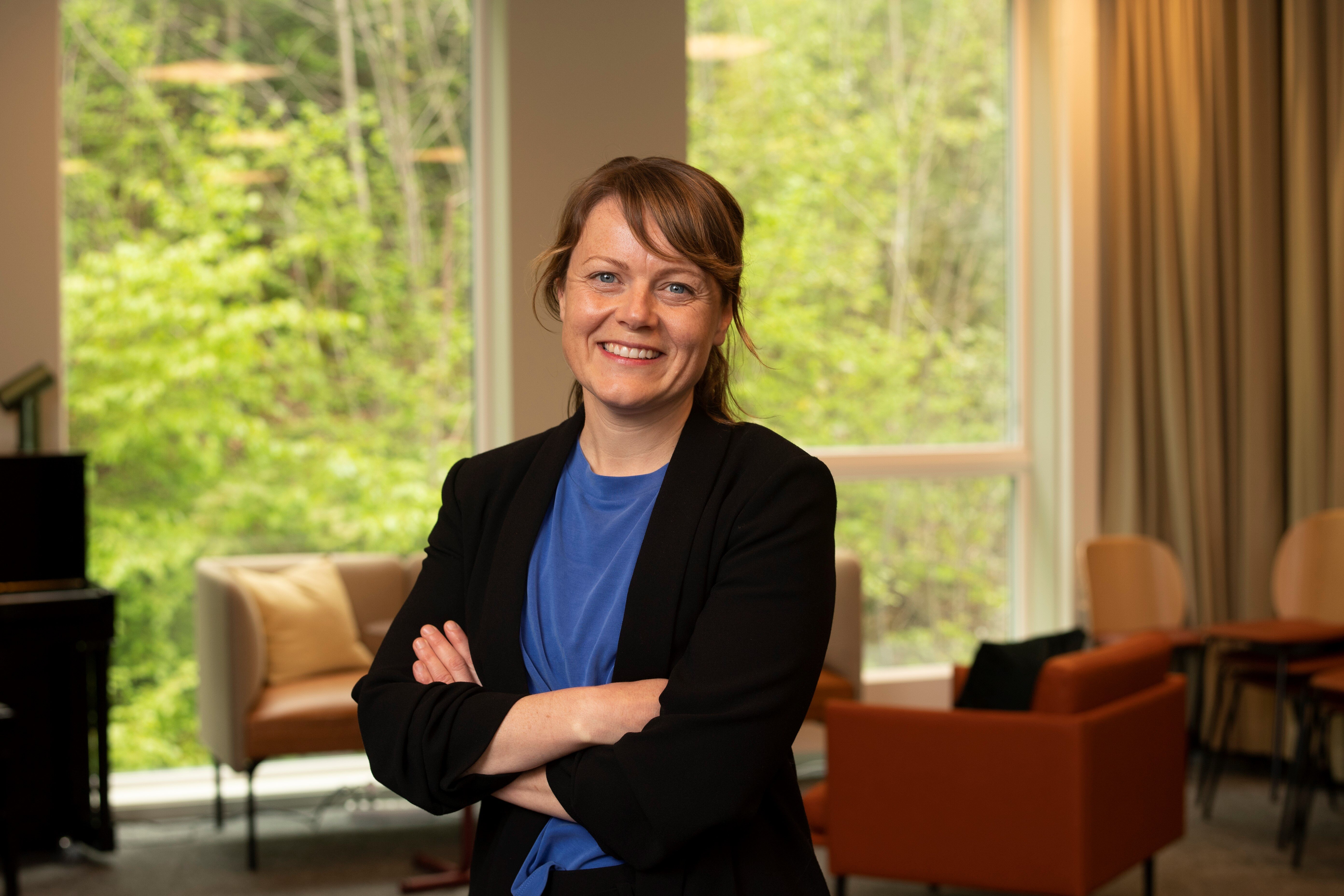 Bildet viser innleggsforfatter Aina Kolle. Hun smiler til kamera og holder armene i kors.