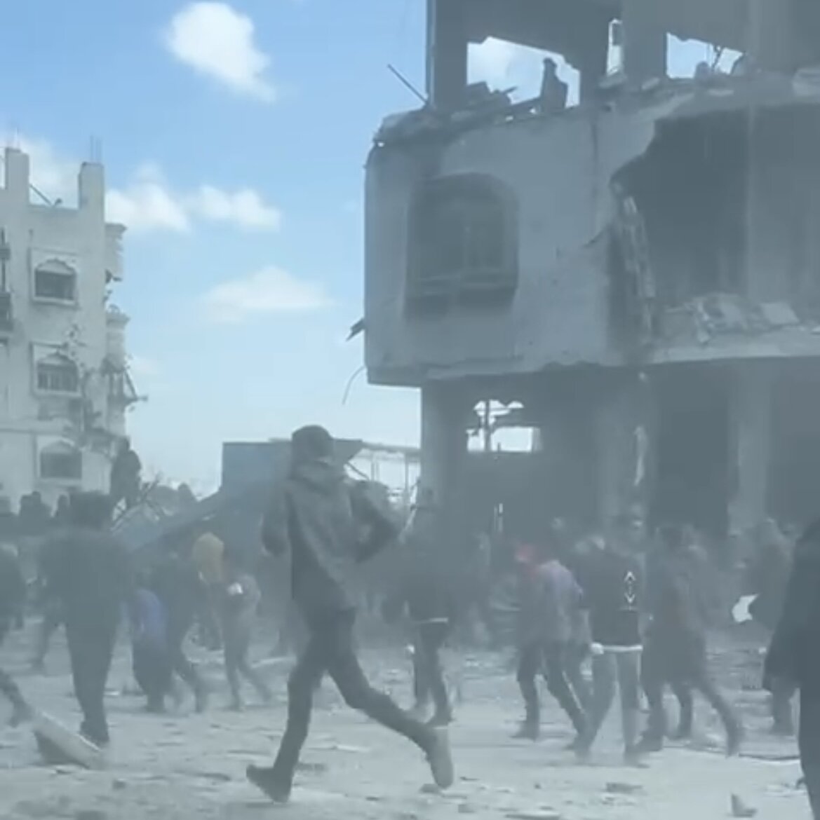 Bildet viser mennesker som løper i ruiner.