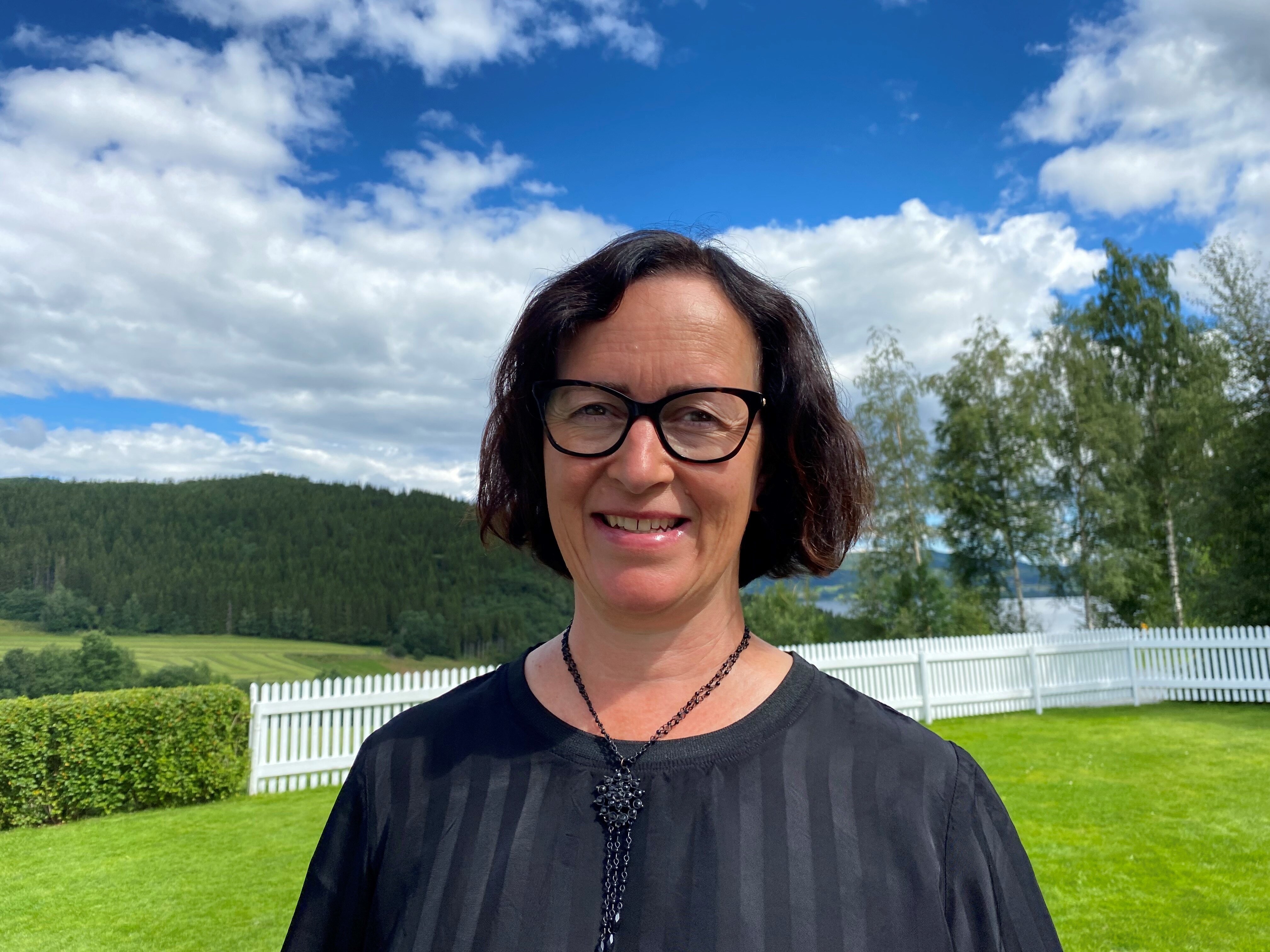 Elisabeth Sjaastad på en gressplen med blå himmel i bakgrunnen