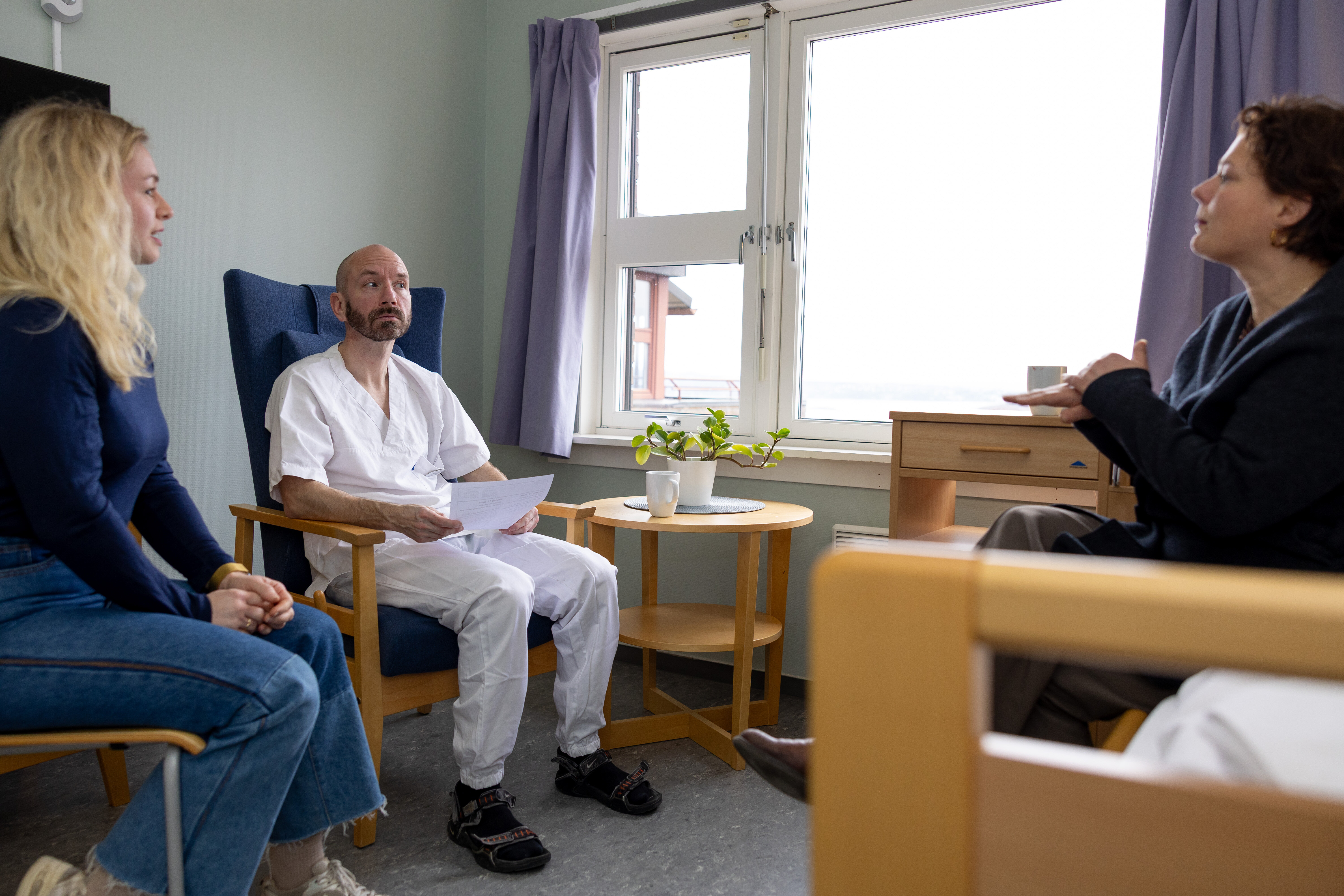 Bildet viser en sykepleier, en tolk og en døv pasient som er i samtale