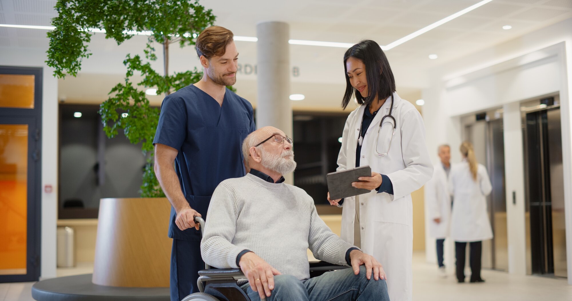 Bildet viser en pasient i rullestol med helsepersonell rundt seg