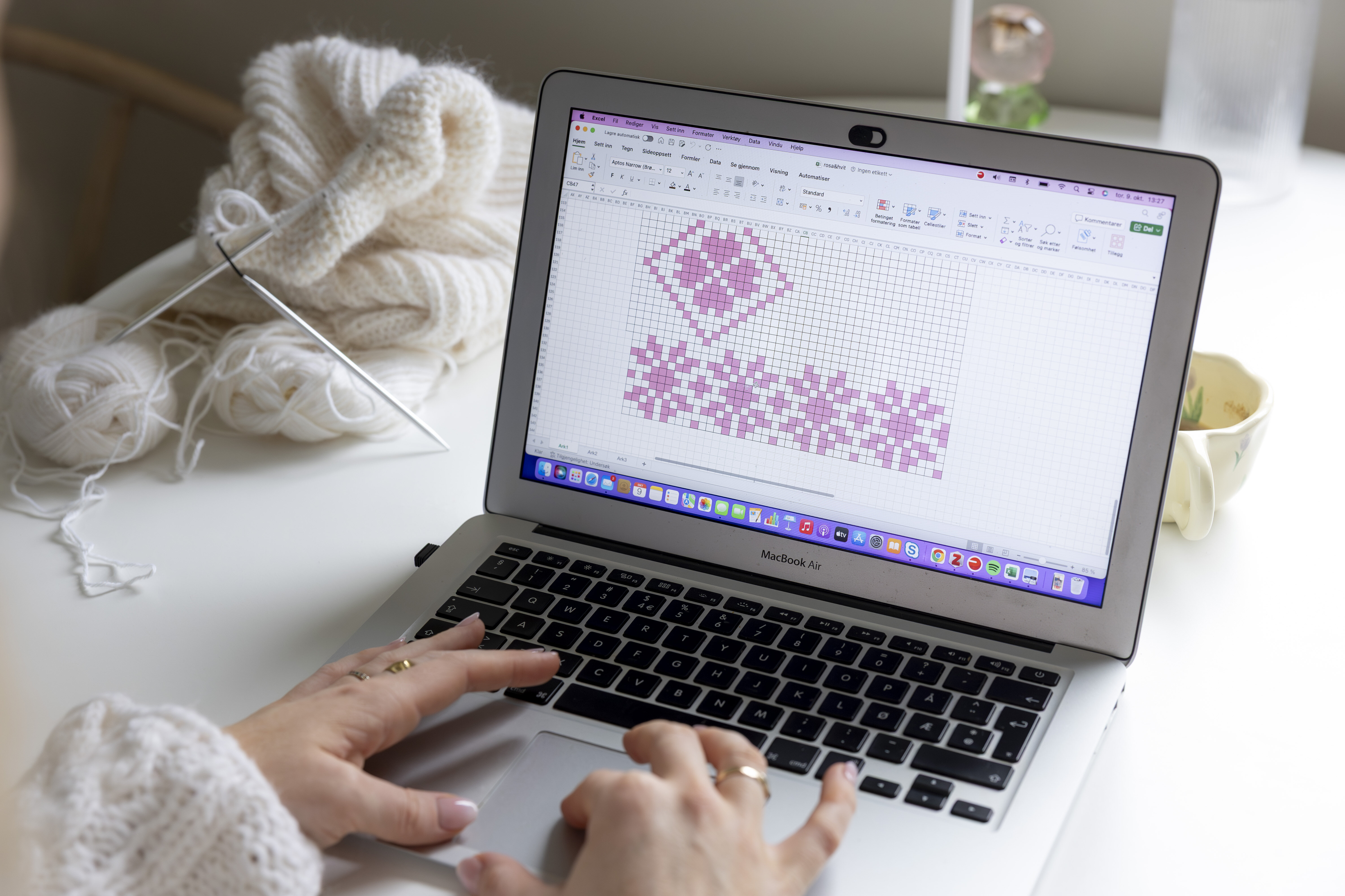 Bildet viser en som lager strikkedesign på datamaskin.