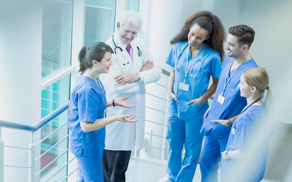 Bildet viser sykepleiere og en lege som snakker sammen i korridoren