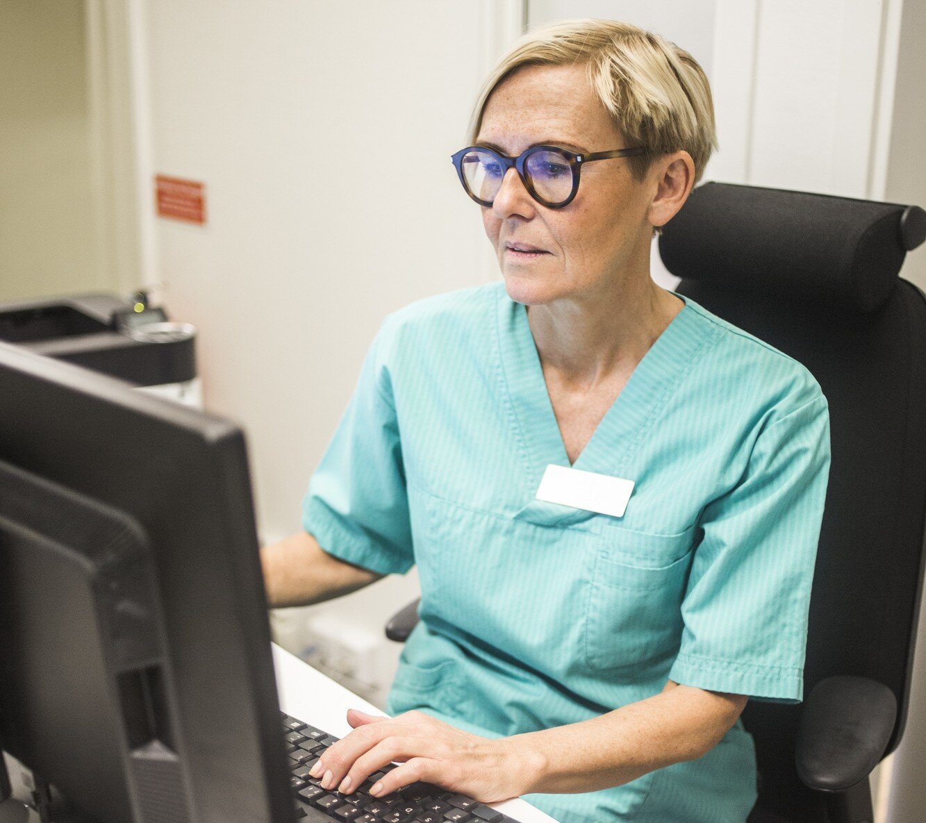 Bilder viser en sykepleier som skriver på en PC