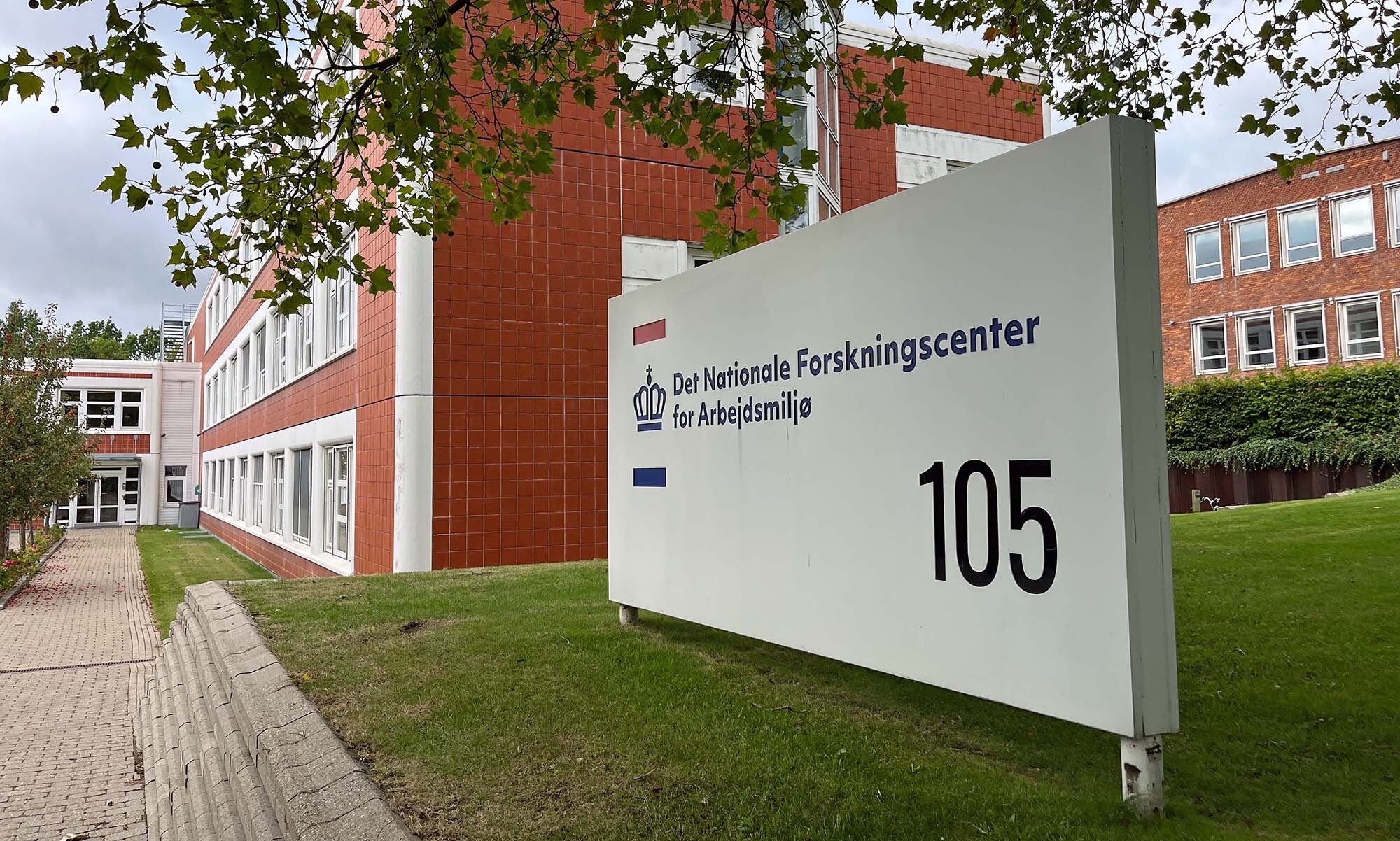 Bildet viser et skilt som viser vei til det nasjonale forskningssenteret for arbeidsmiljø i Danmark.