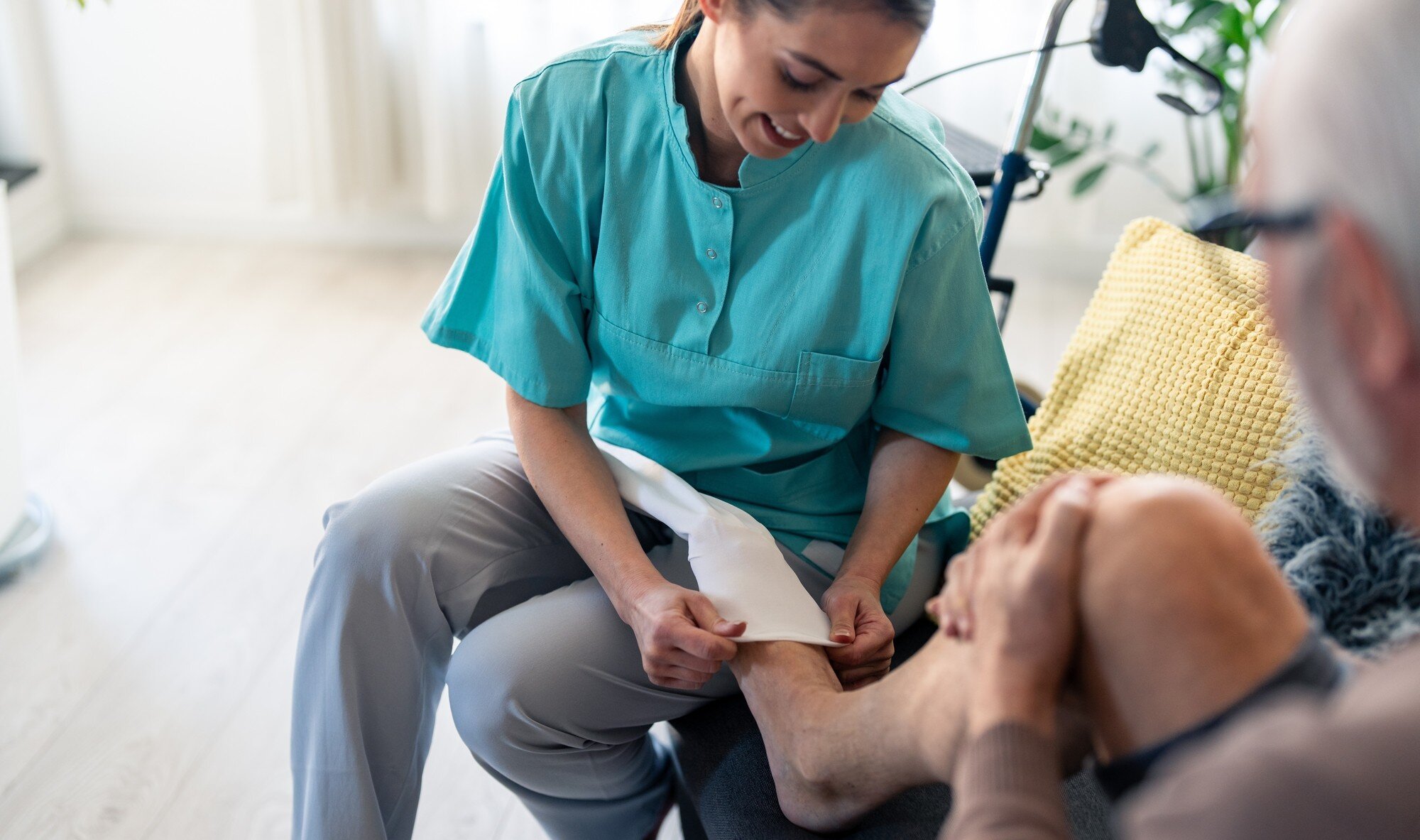 Bildet viser en sykepleier som hjelper en mann med å ta på kompresjonsstrømper