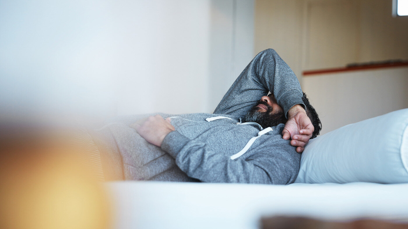 Bildet viser en ung mann som ligger på sofaen med høyre arm over hodet.
