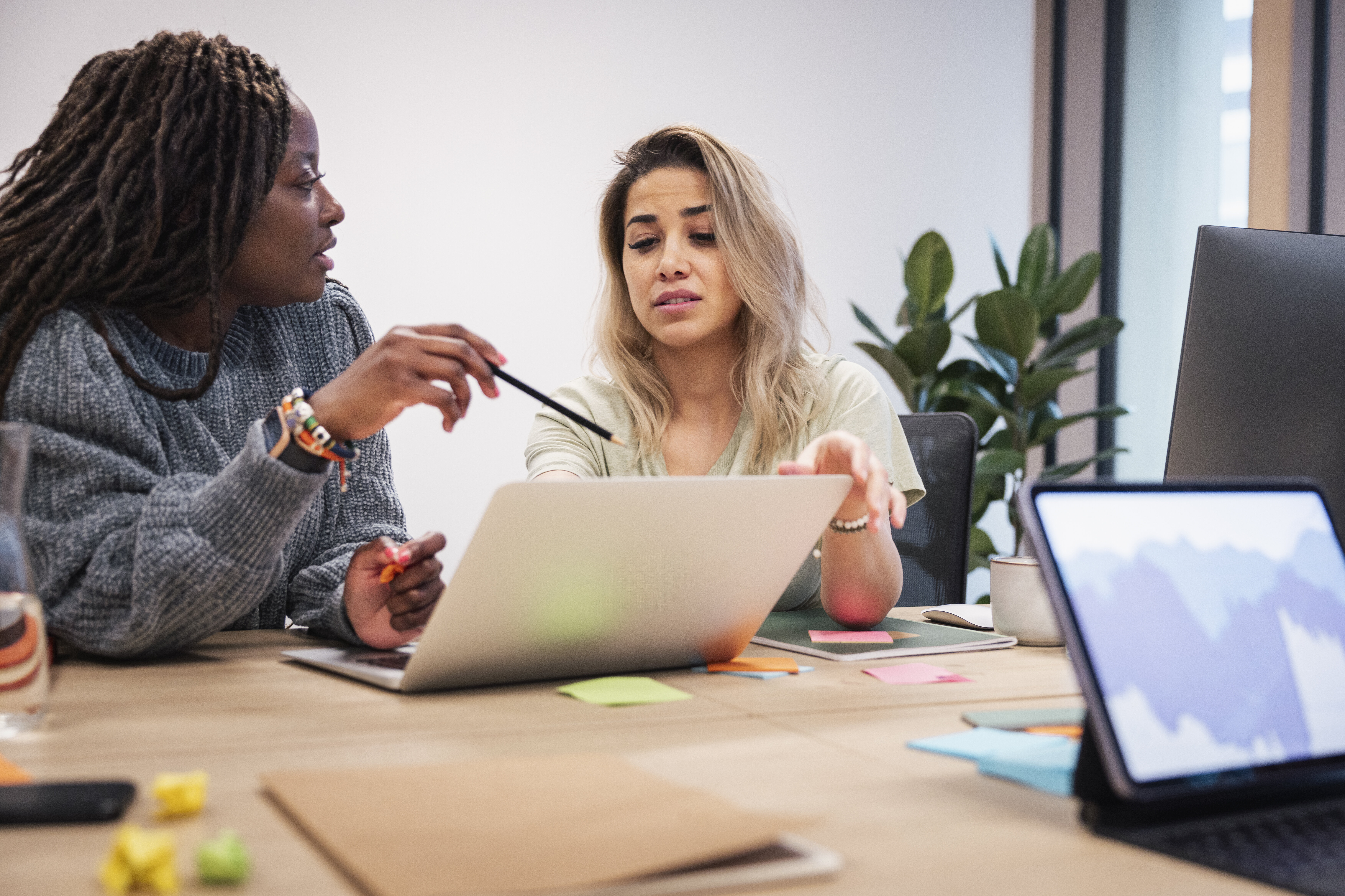 Bildet viser to kvinner som sitter og diskuterer foran en PC