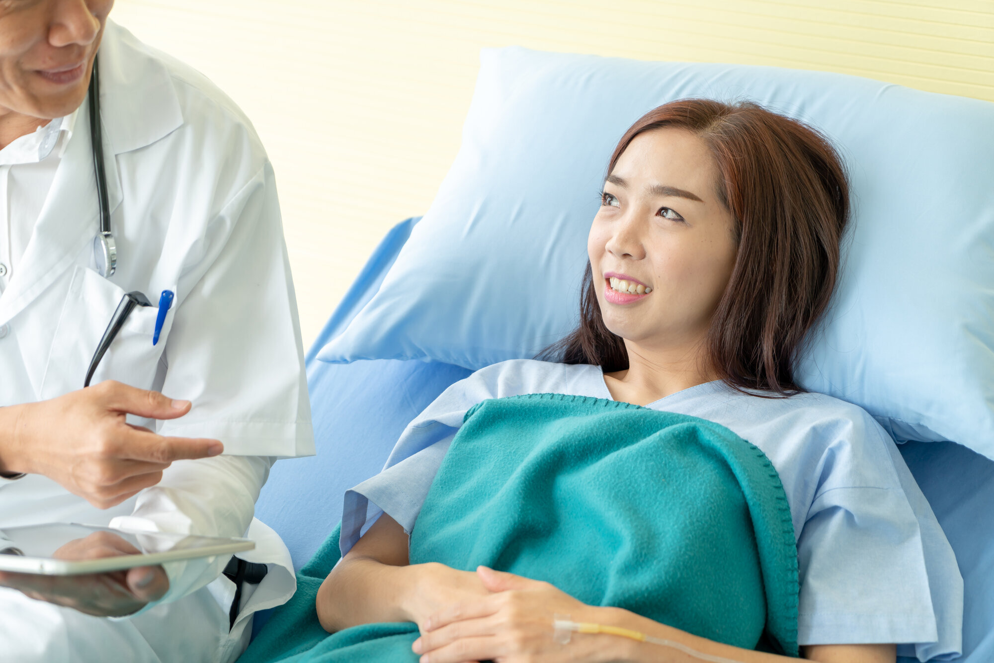 Lege på visitt hos kvinnelig pasient i sykeseng