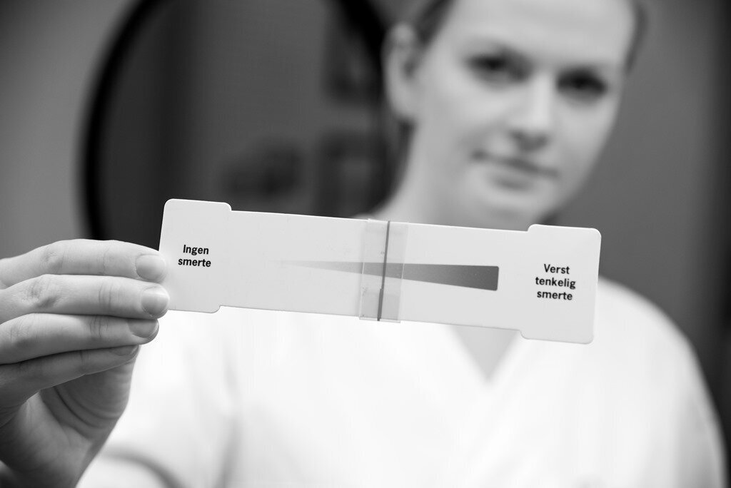 Sykepleier holder et smerteskåringsverktøy