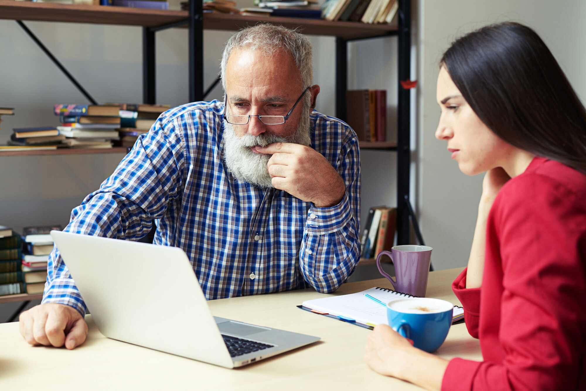 Ung jente viser en eldre mann noe på PC-en sin på et kontor