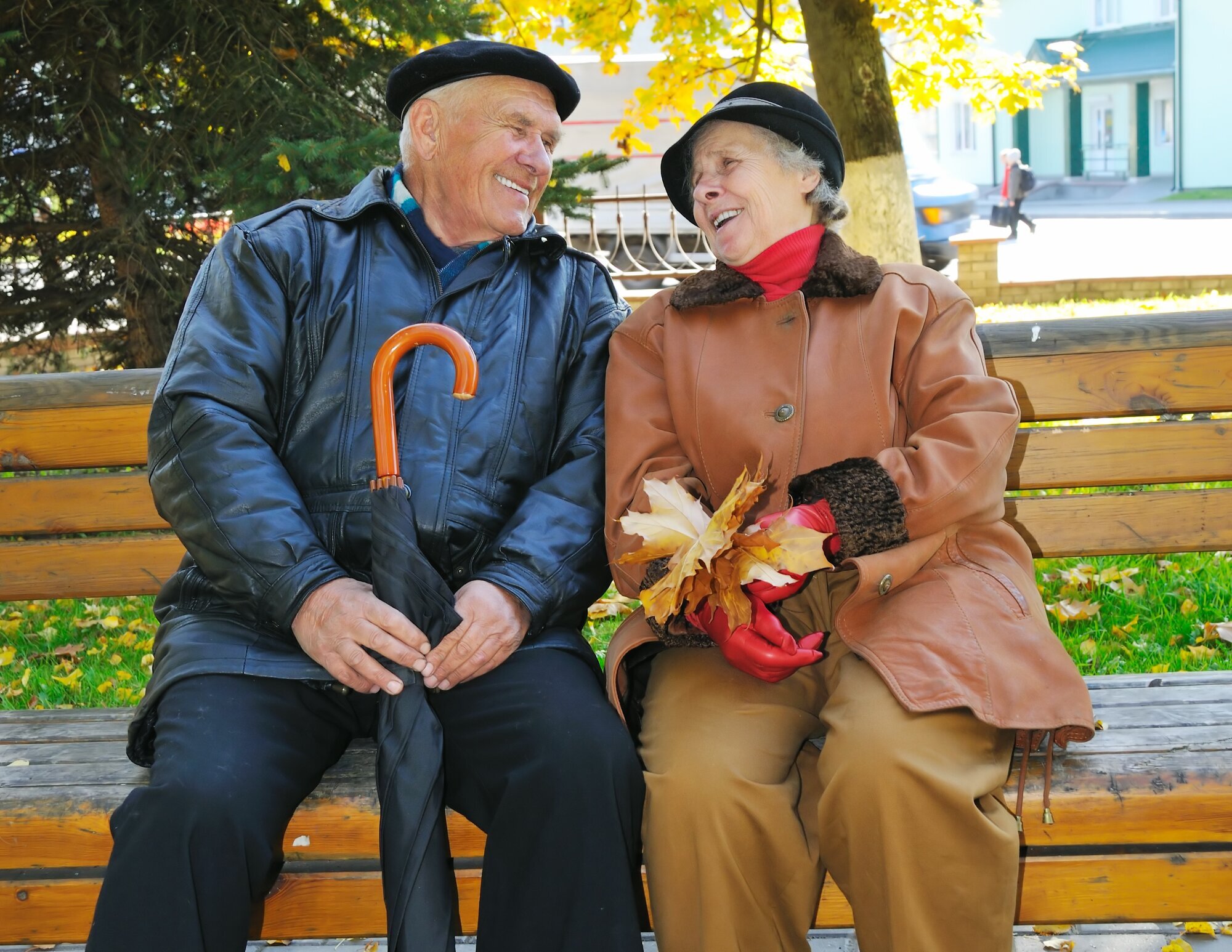 Bildet viser to eldre mennesker som sitter på en benk og ler.
