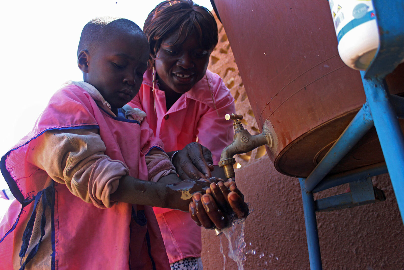 Voksen hjelper barn med håndvask