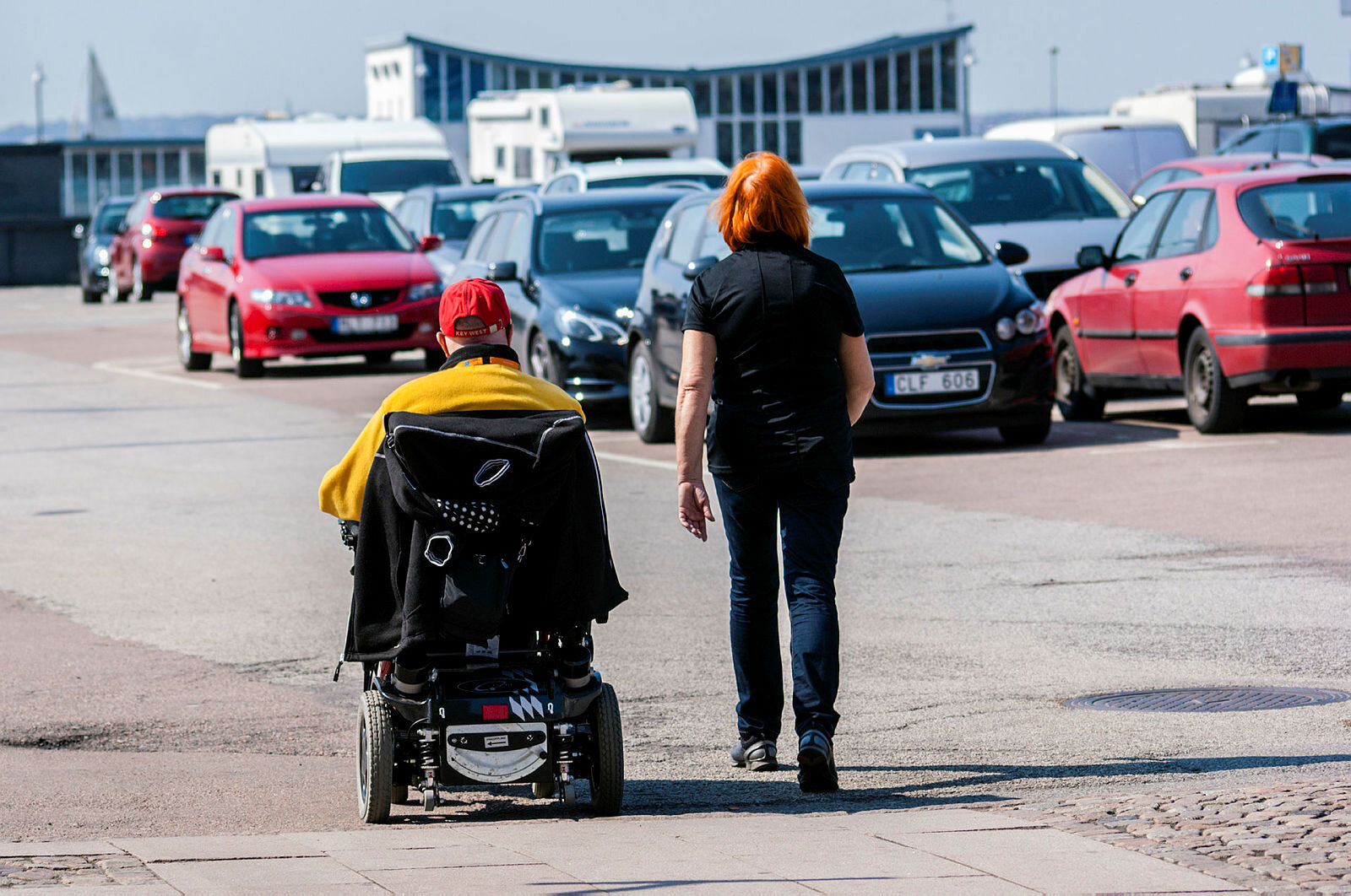 Rullestolbruker og gående på en parkeringsplass