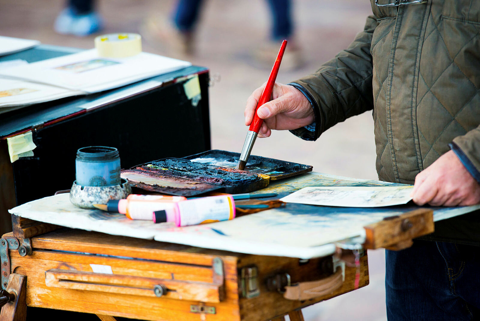 Bildet viser hender som tar maling på en pensel for å male et bilde
