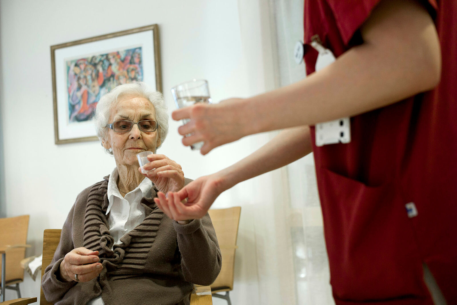 Bildet viser en eldre kvinne som får utdelt medisiner