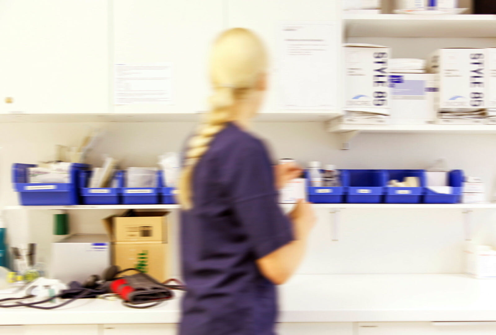 Bildet viser en sykepleier som finner frem medisiner på et medisinrom.