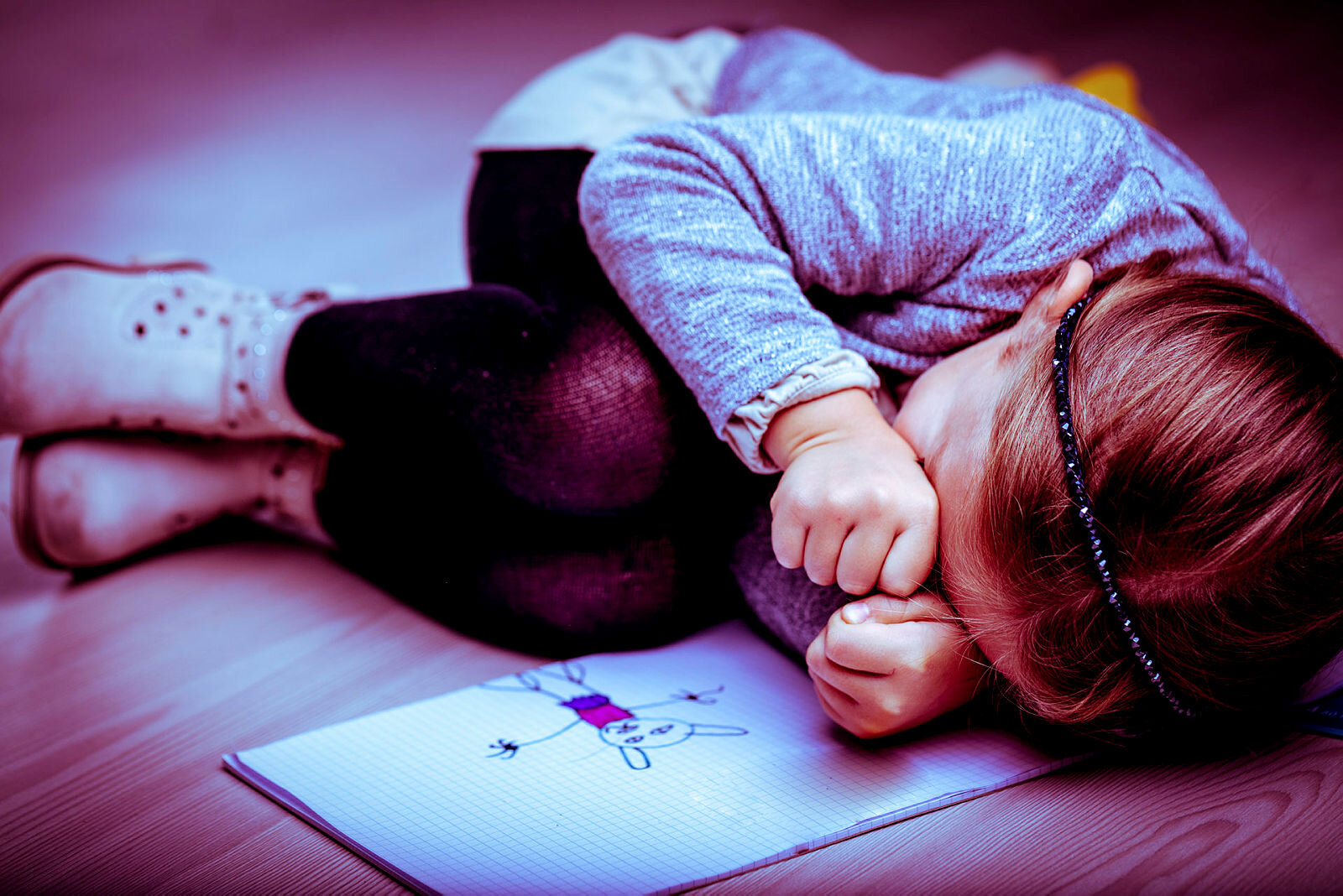 Bildet viser en liten jente i fosterstilling ved siden av en tegning 