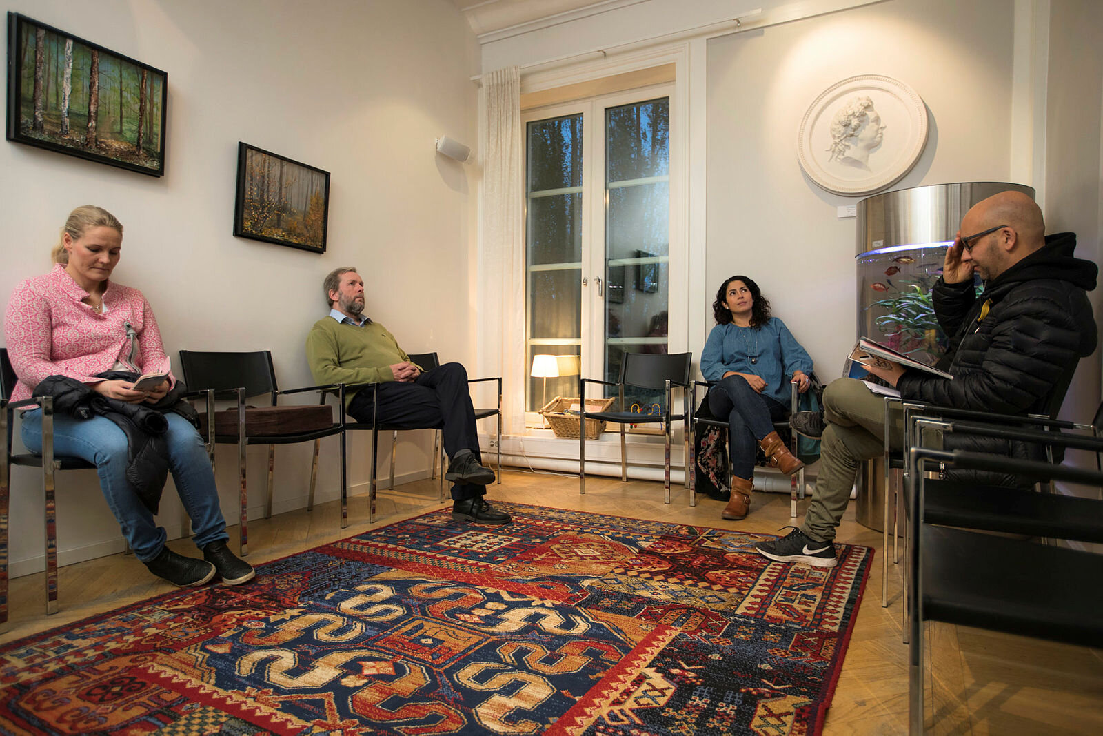 Bildet viser fire personer som sitter i et venterom