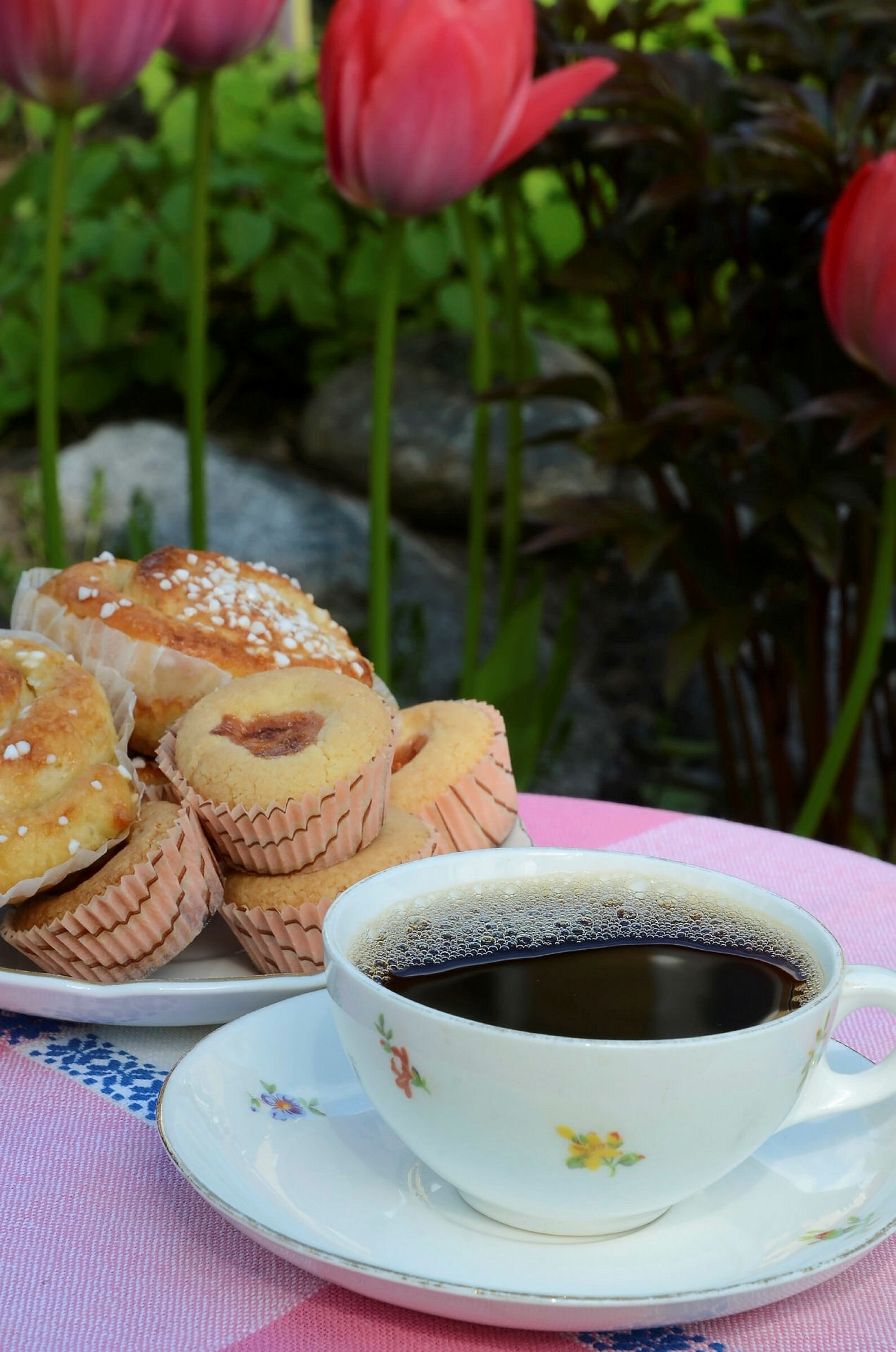 Kaffekopp og muffins på et bord med duk.