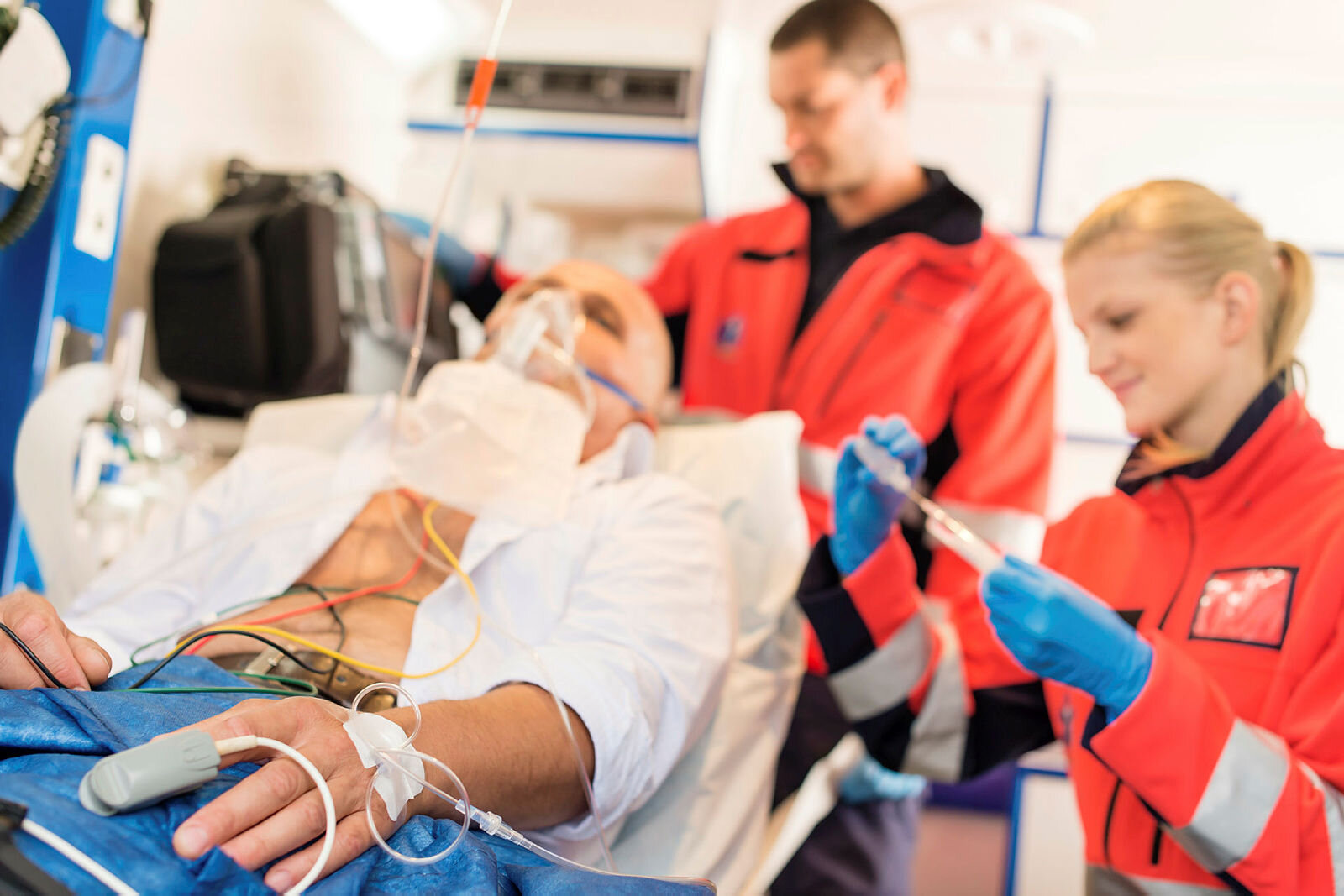 Bildet viser en pasient som blir behandlet i en ambulanse av to ambulansepersonell.