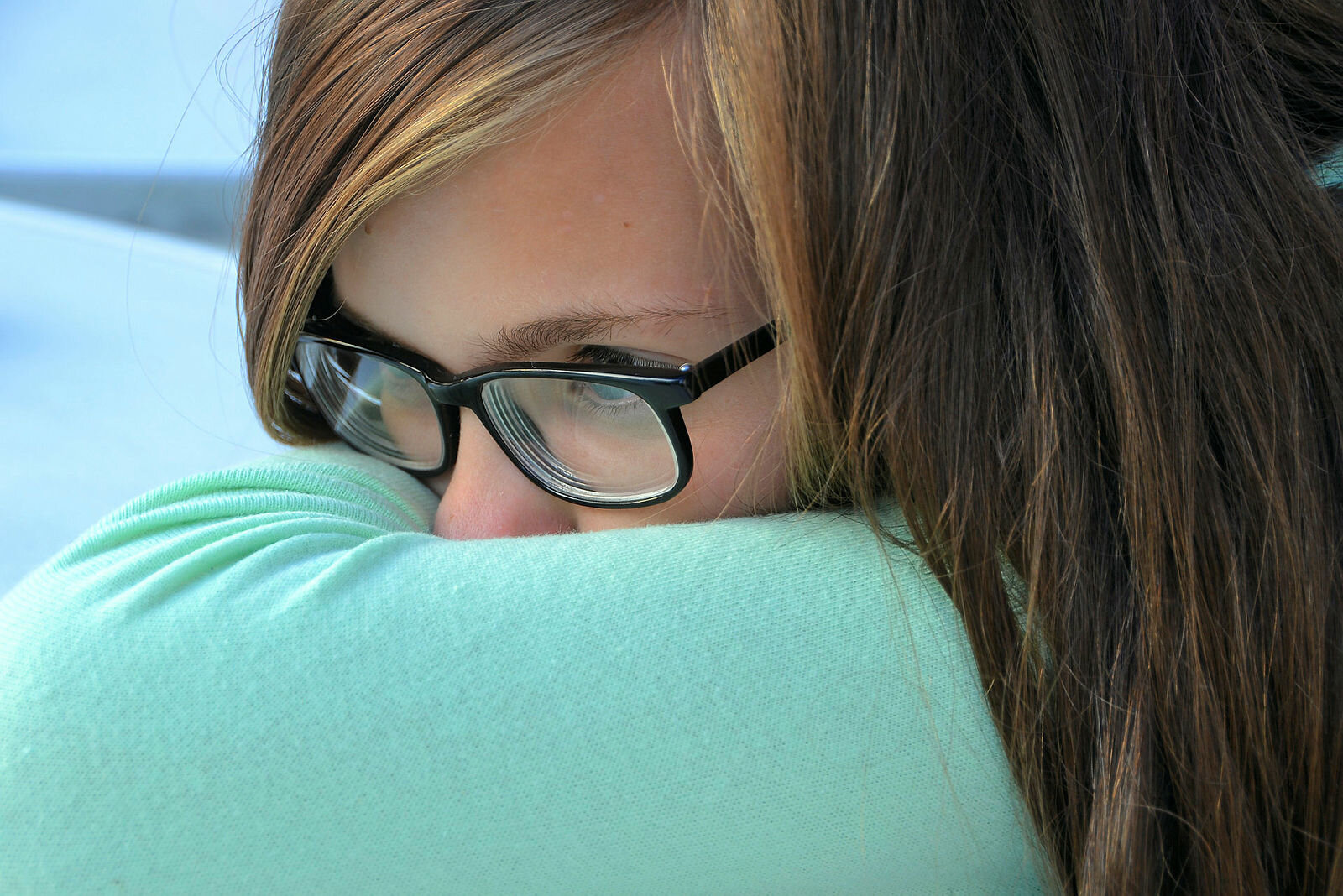 Bildet viser en ung jente som gjemmer ansiktet sitt i en pute