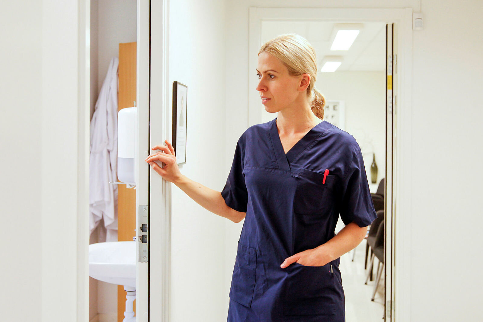 Bildet viser en sykepleier som kikker inn døren til rommet pasienten er på