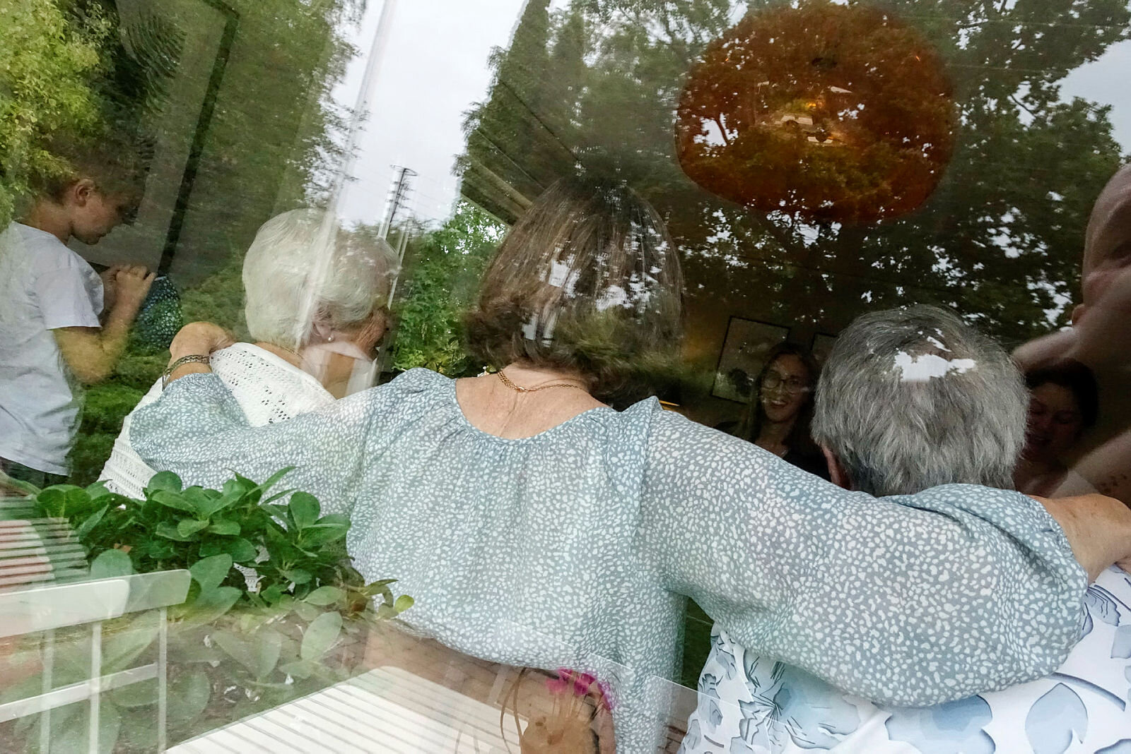 Eldre personer sett bakfra gjennom et vindu.