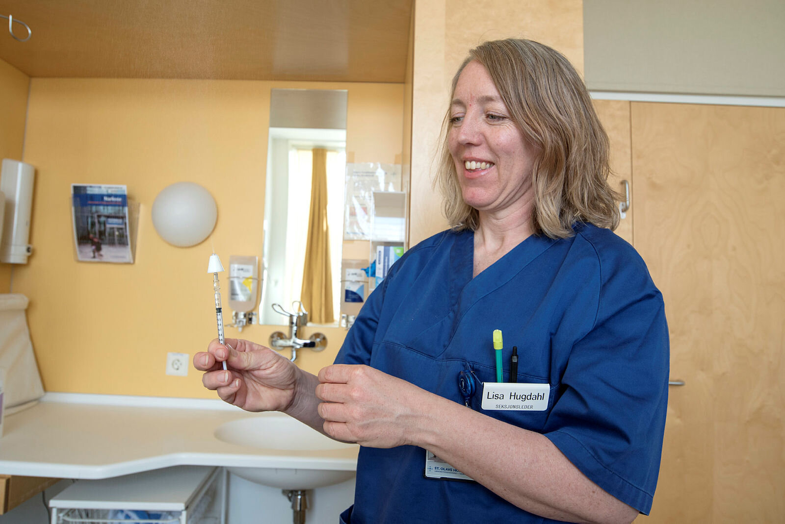 Bildet viser Lisa Hugdahl som holder en injeksjonssprøyte påsatt et forstøverforstykke.