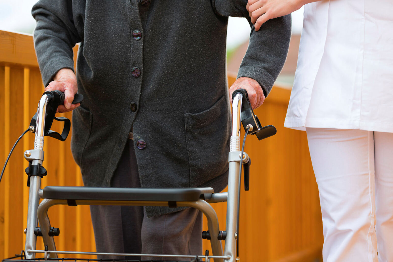 Sykepleier støtter person med rullator.