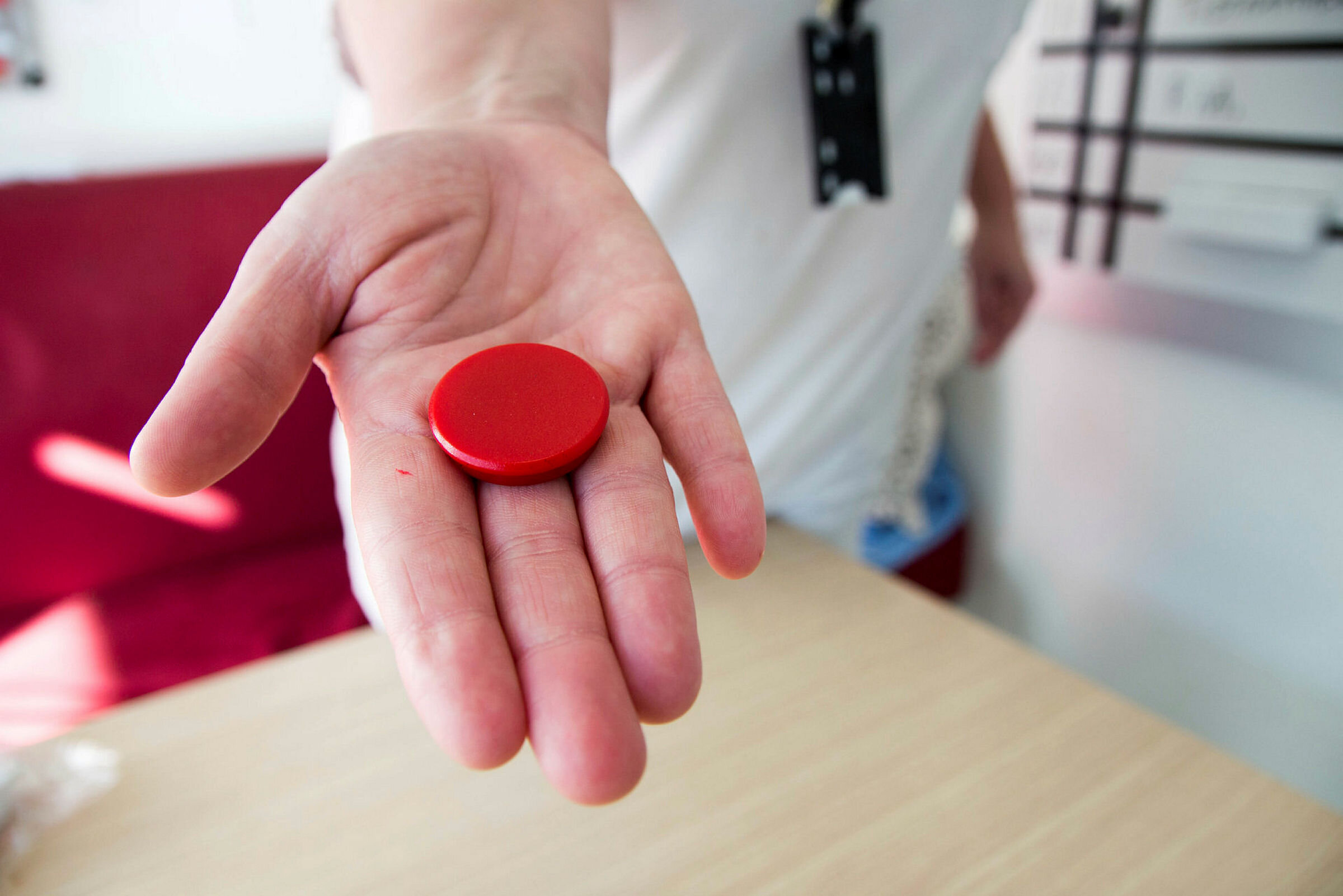 Bildet viser en hånd som holder en rød magnet.