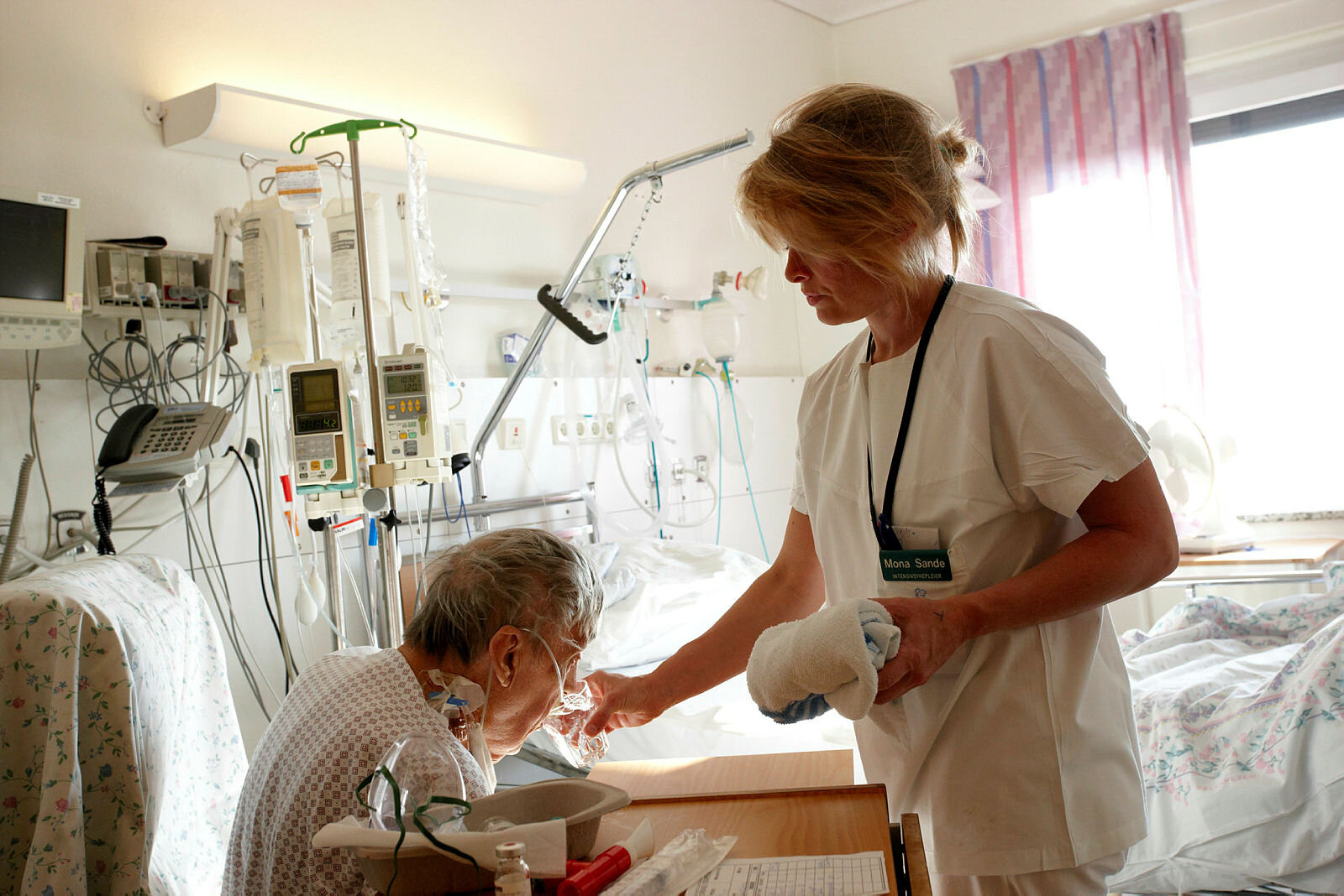 Sykepleier gir pasient noe å drikke