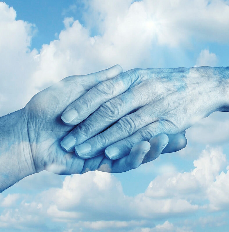 Bildet viser hender som holder hverandre med himmel og skyer i bakgrunnen. 