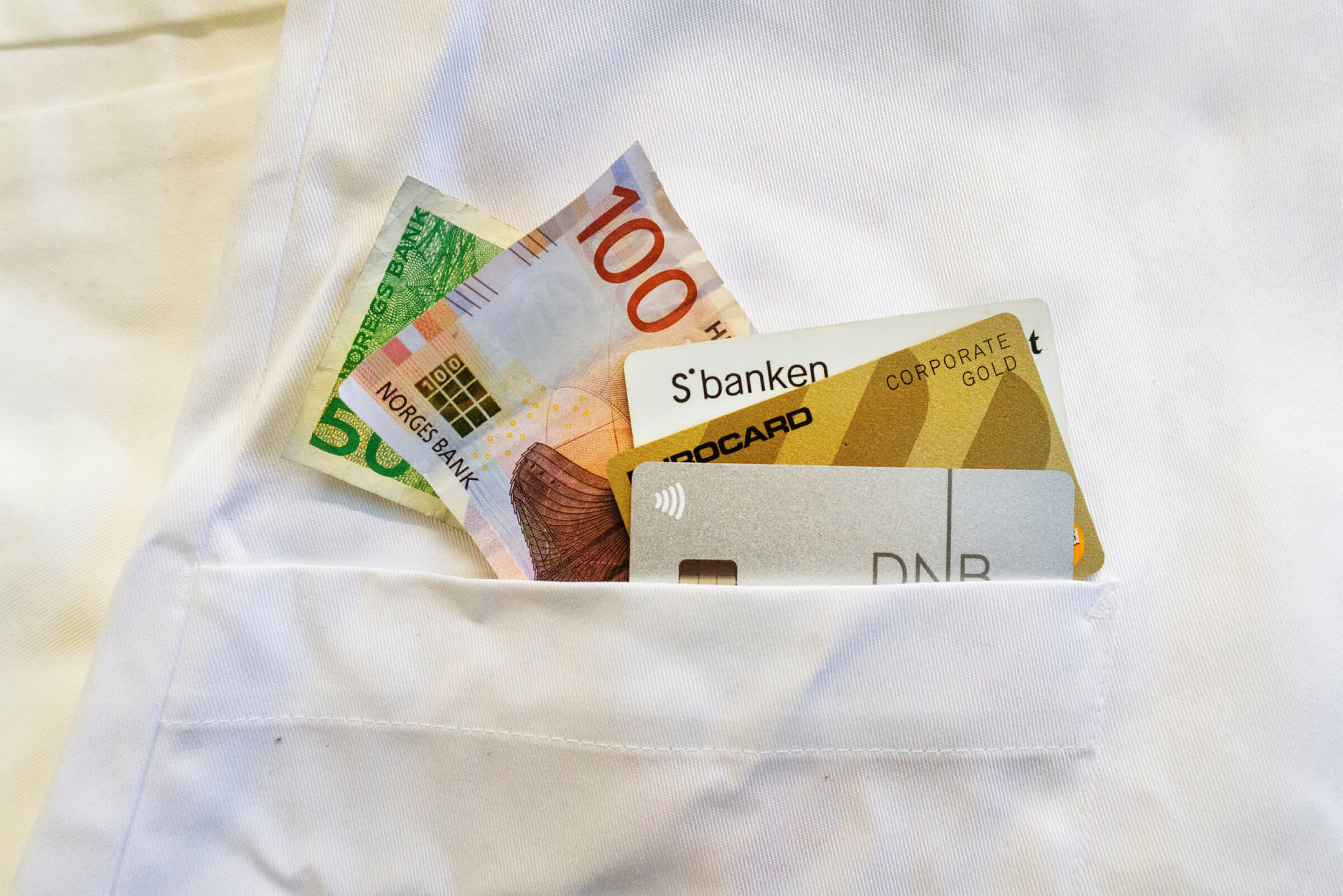 Penger og bankkort, i lommen på en sykepleieruniform