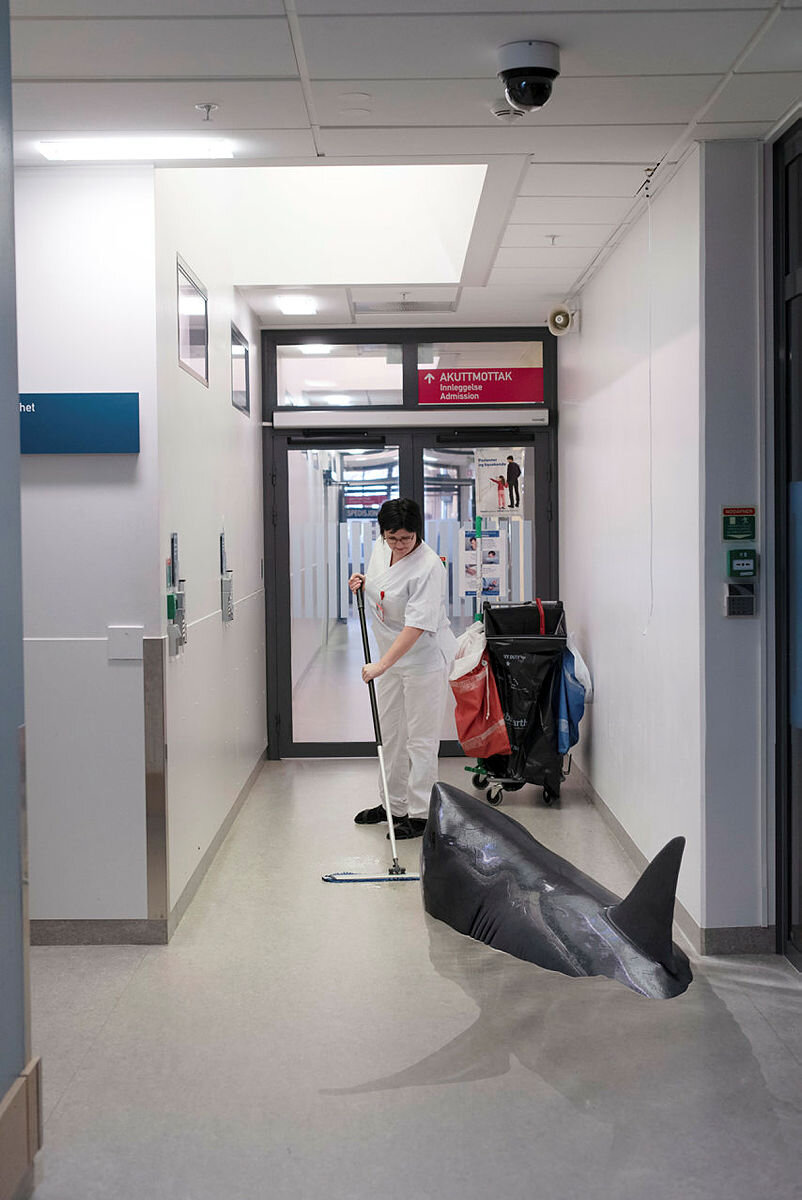 Viser en vaskehjelp i en korridor, hvor en hai "svømmer" rundt