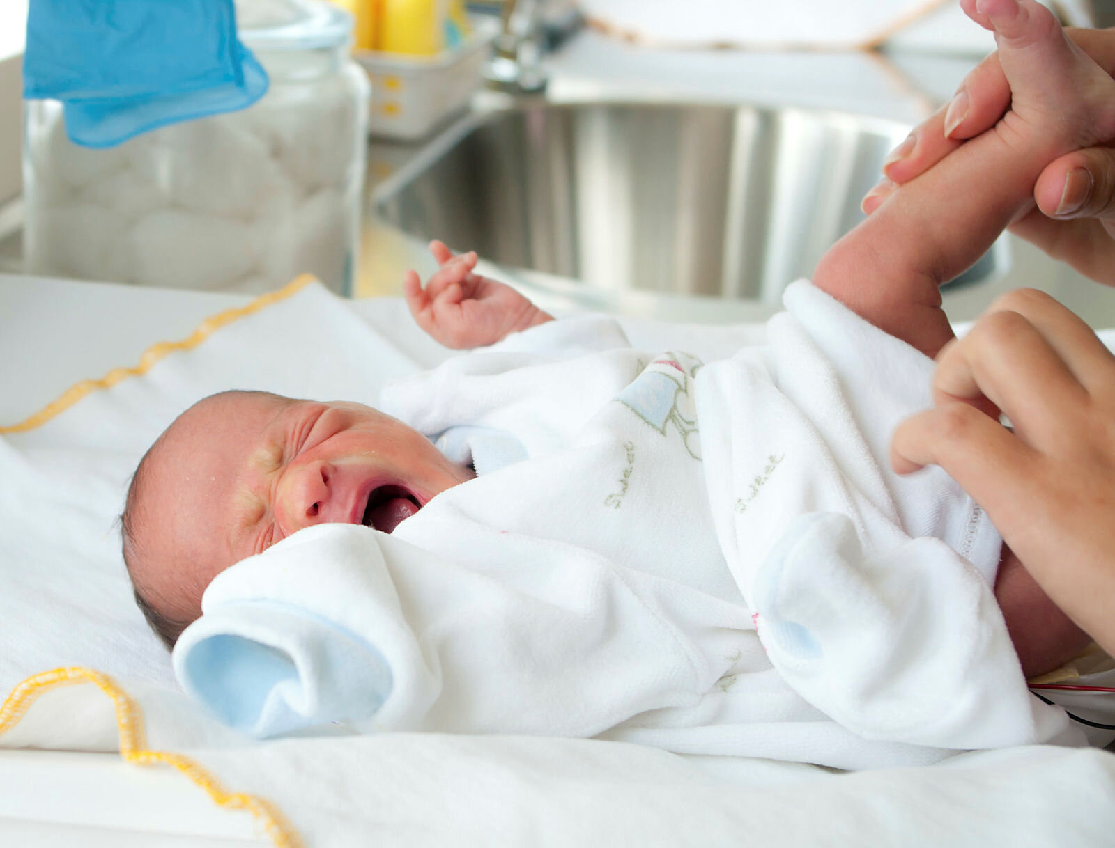 Bildet viser en nyfødt baby som gråter idet hen får skiftet bleie