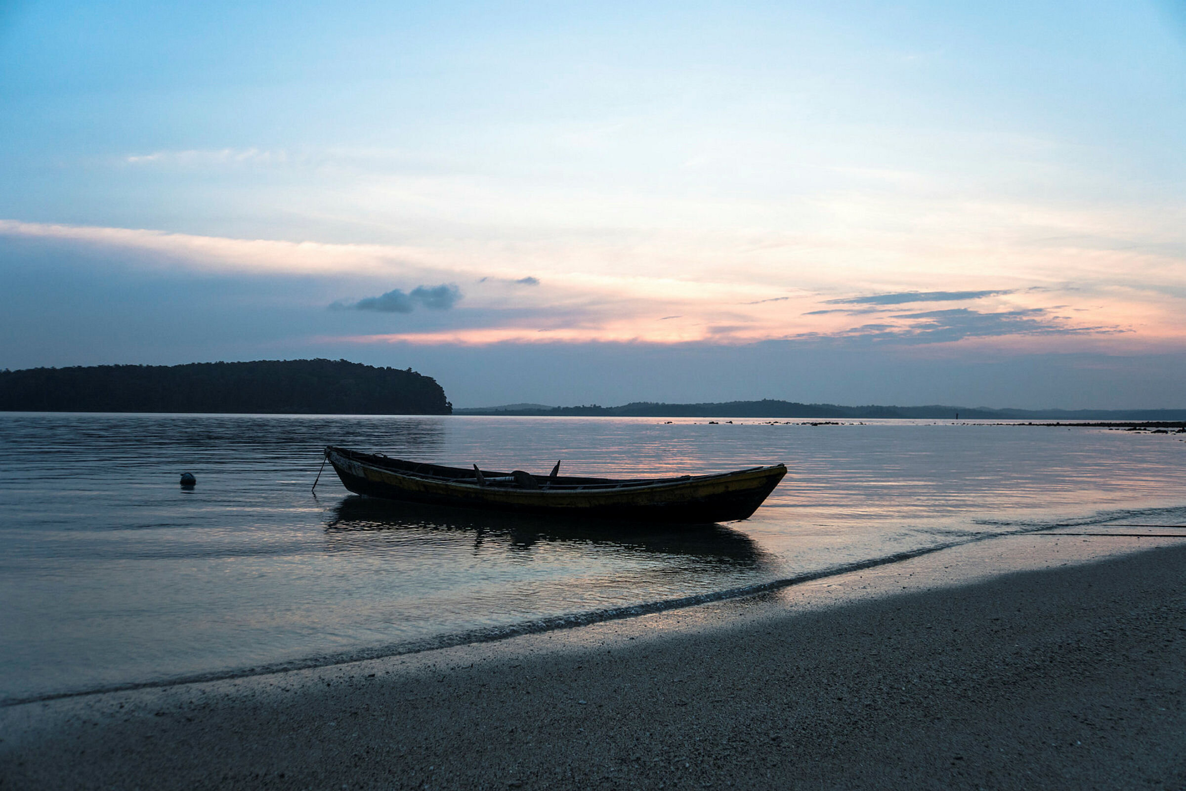 Bildet viser en båt som ligger ved en strand om kvelden