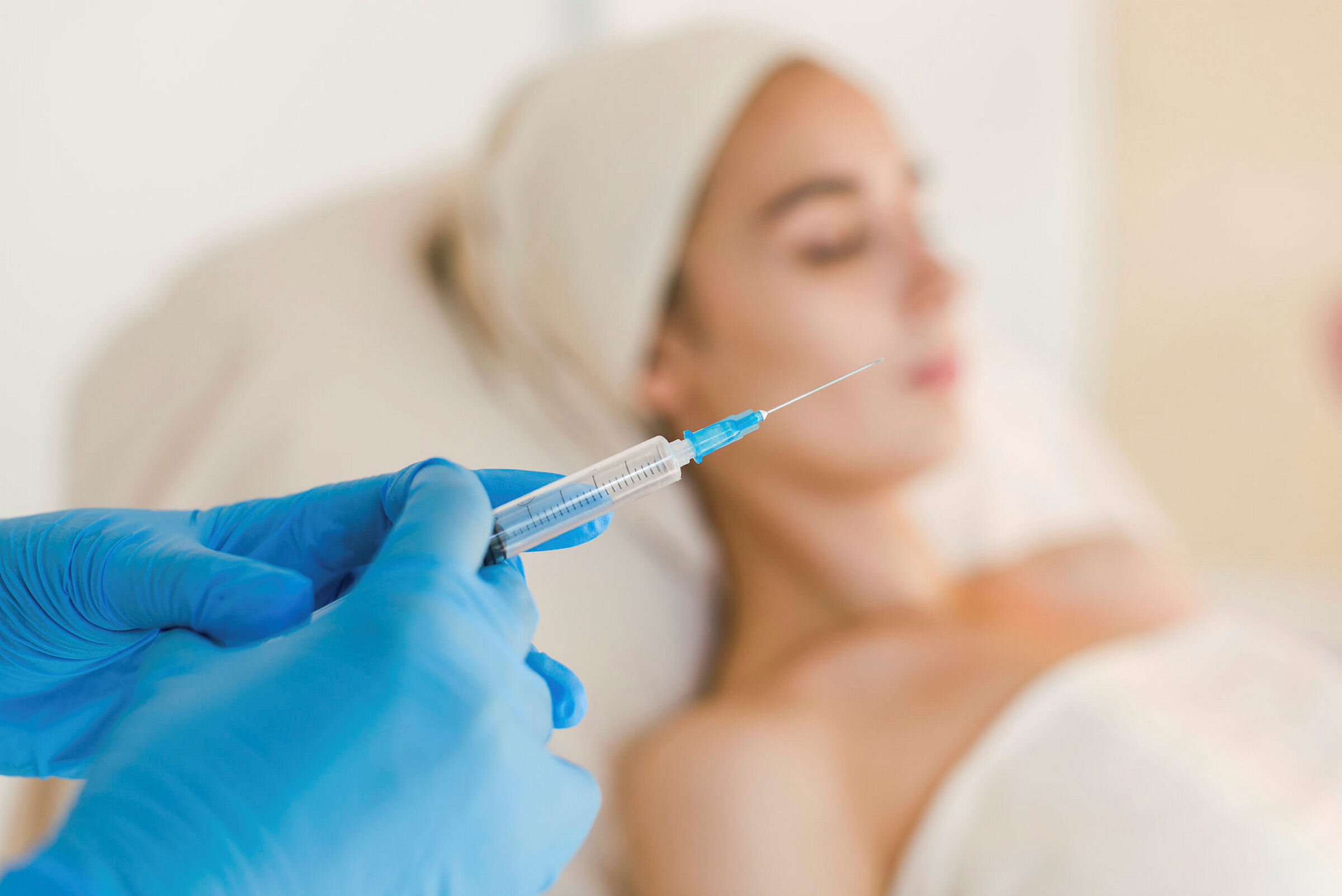 Botox-sprøyte klargjøres i forgrunnen for pasient i bakgrunnen.