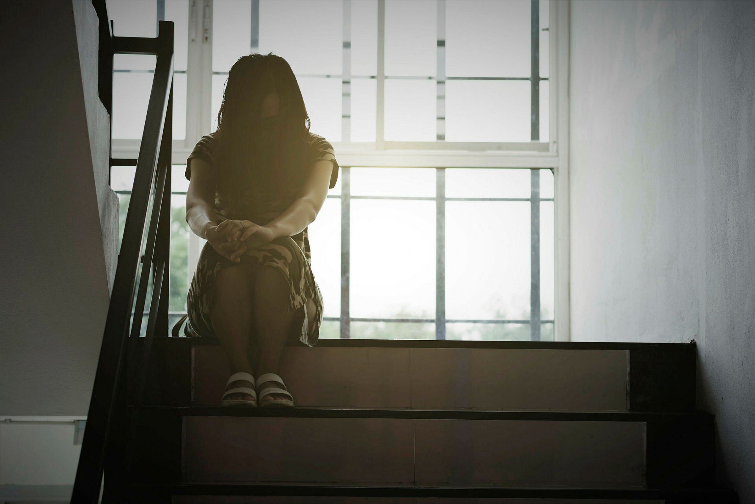 En anonym kvinne sitter i en trappeoppgang