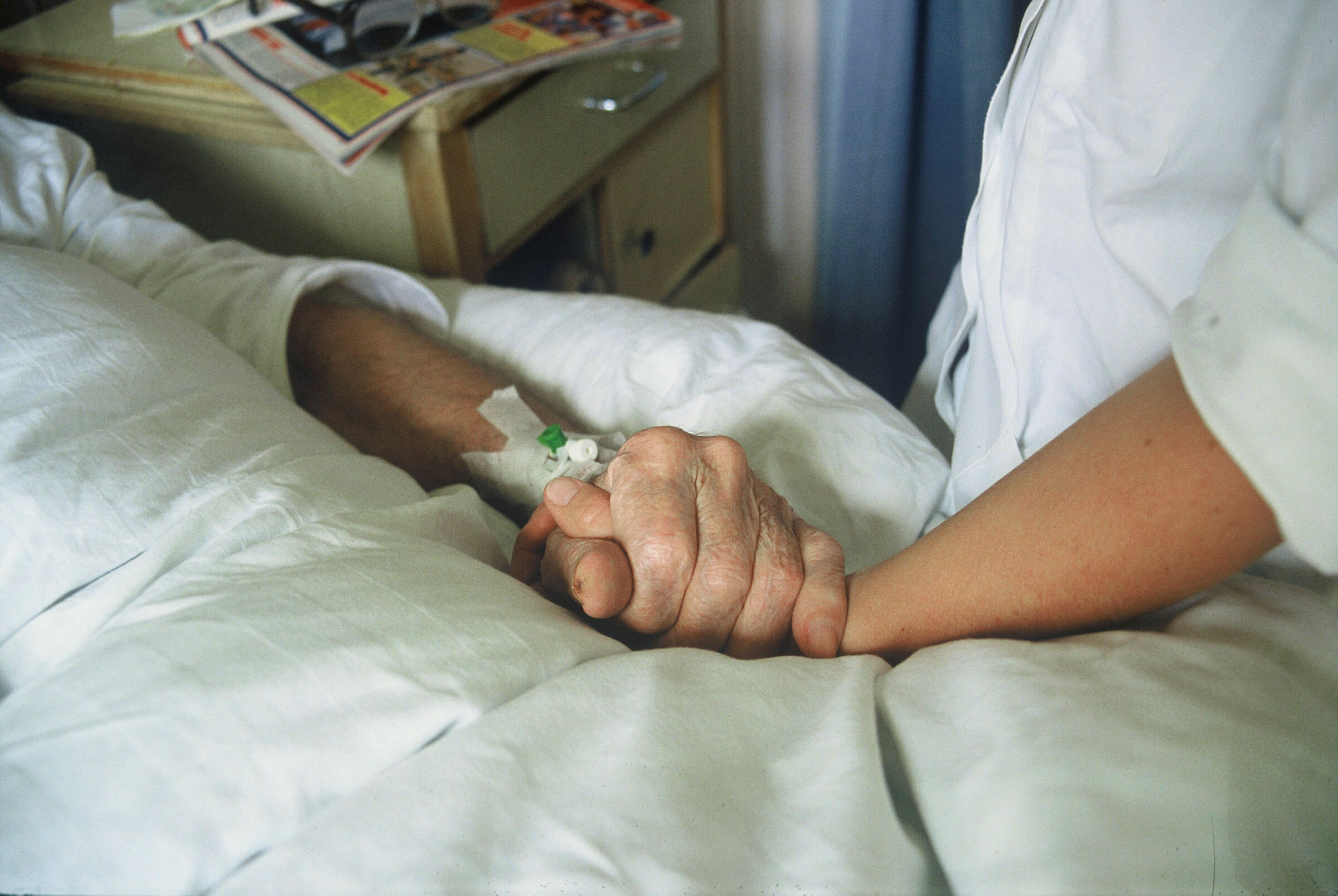 Sykepleier holder eldre pasient i  hånden