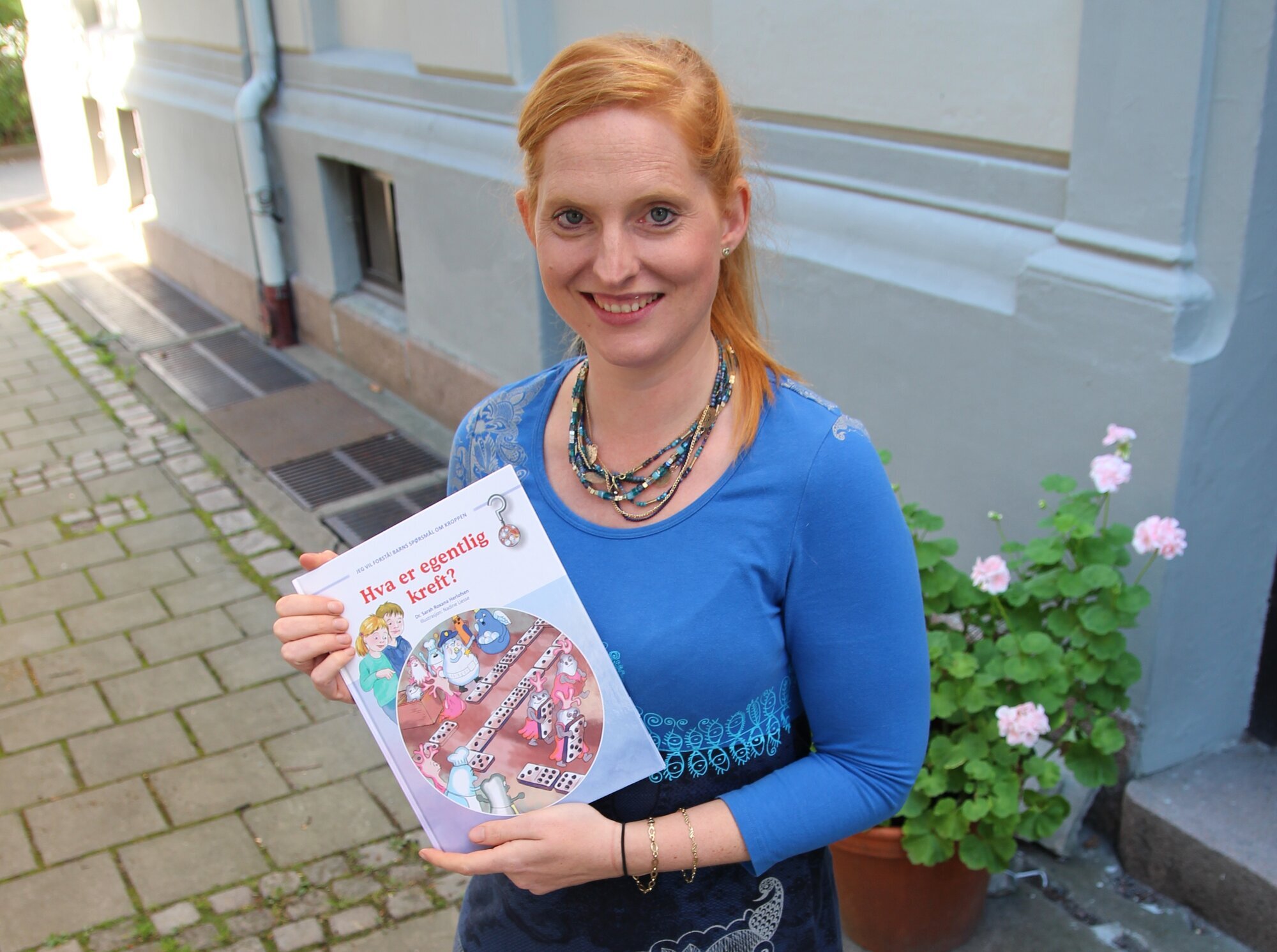 Bildet viser Sarah Roxana Herlofsen som holder frem boken sin.