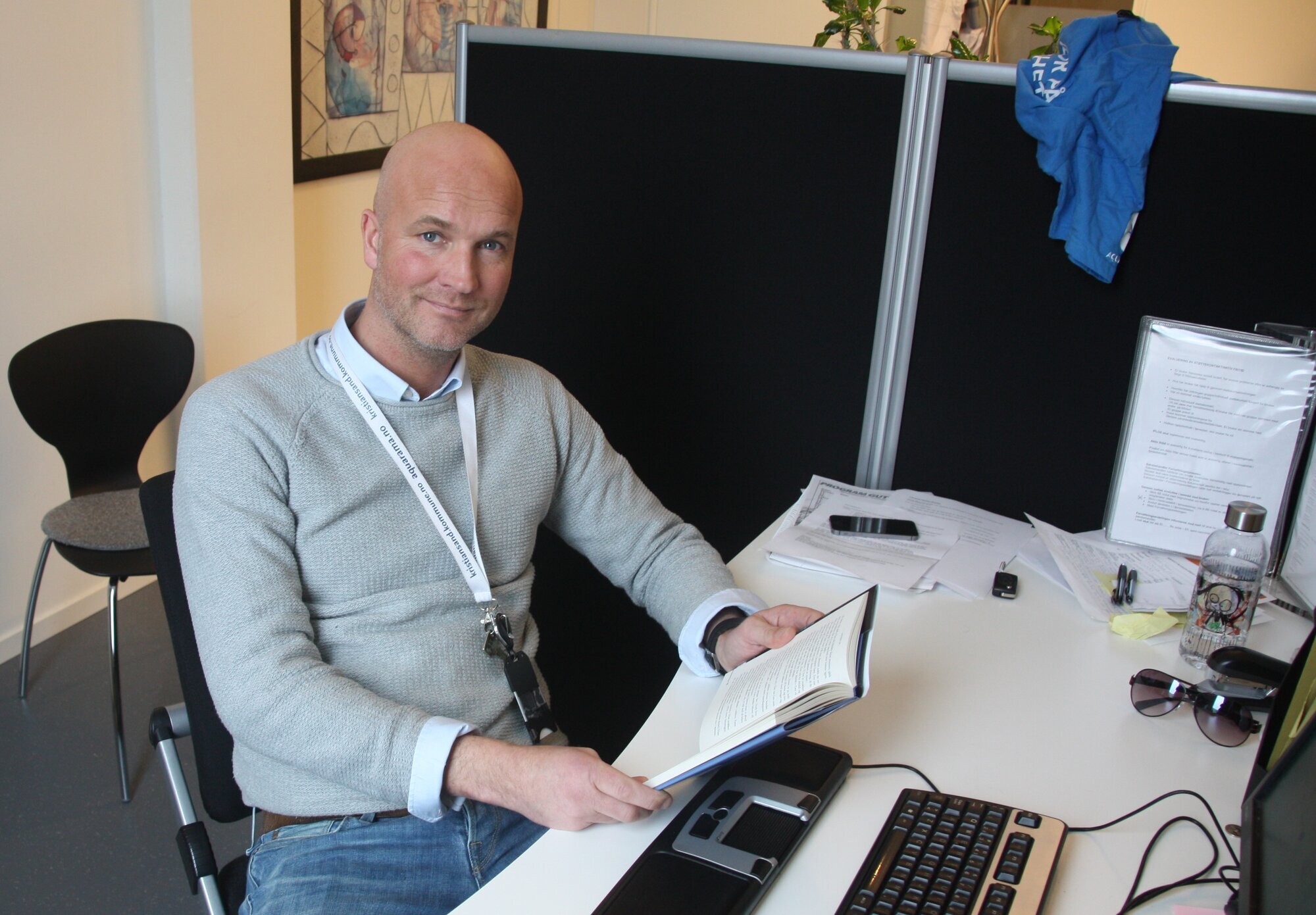 Bildet viser Jan-Erik Vik som sitter foran en datamaskin med bok i hånden.