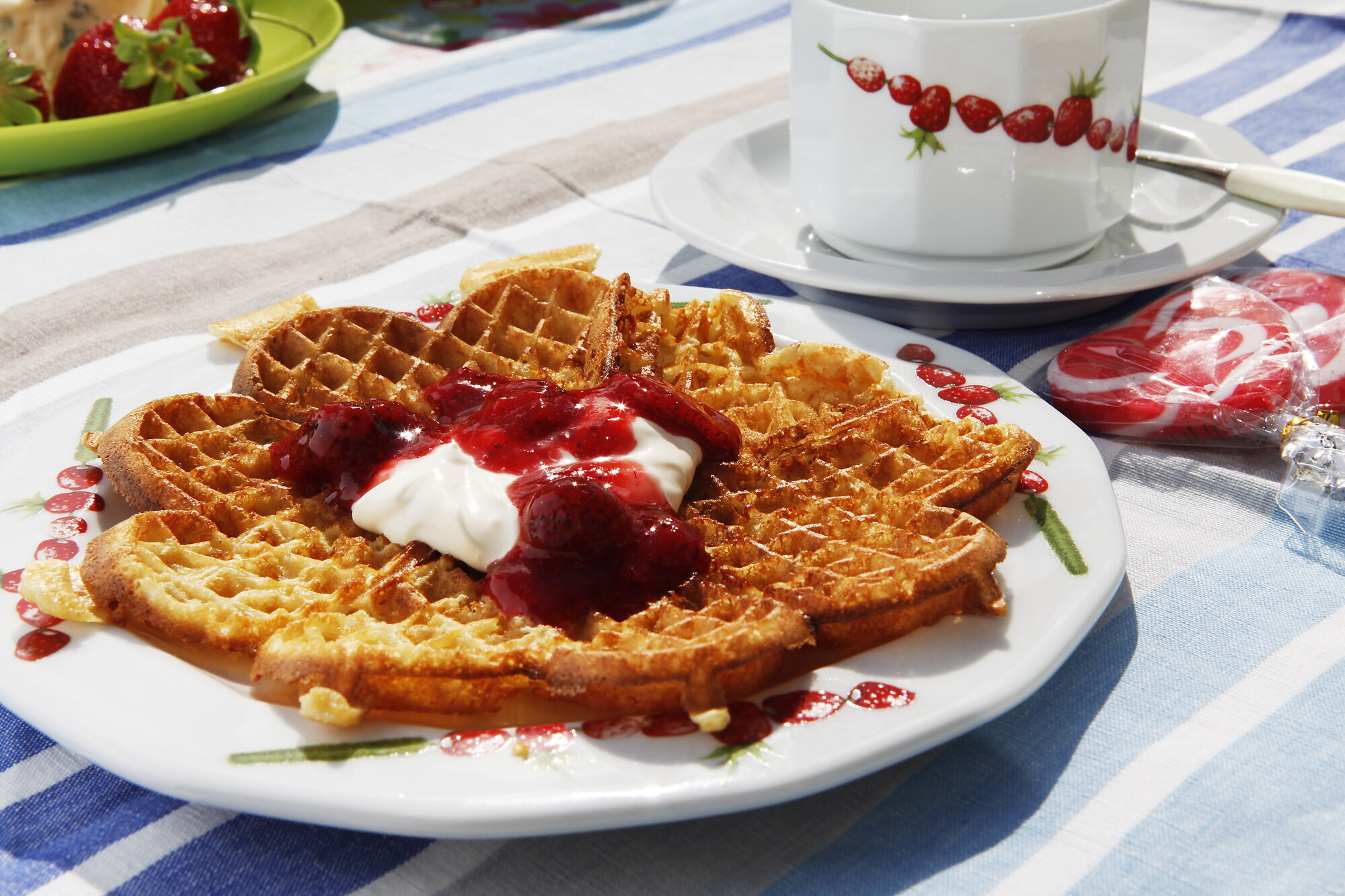 Bildet viser en vaffelplate med syltetøy og rømme.