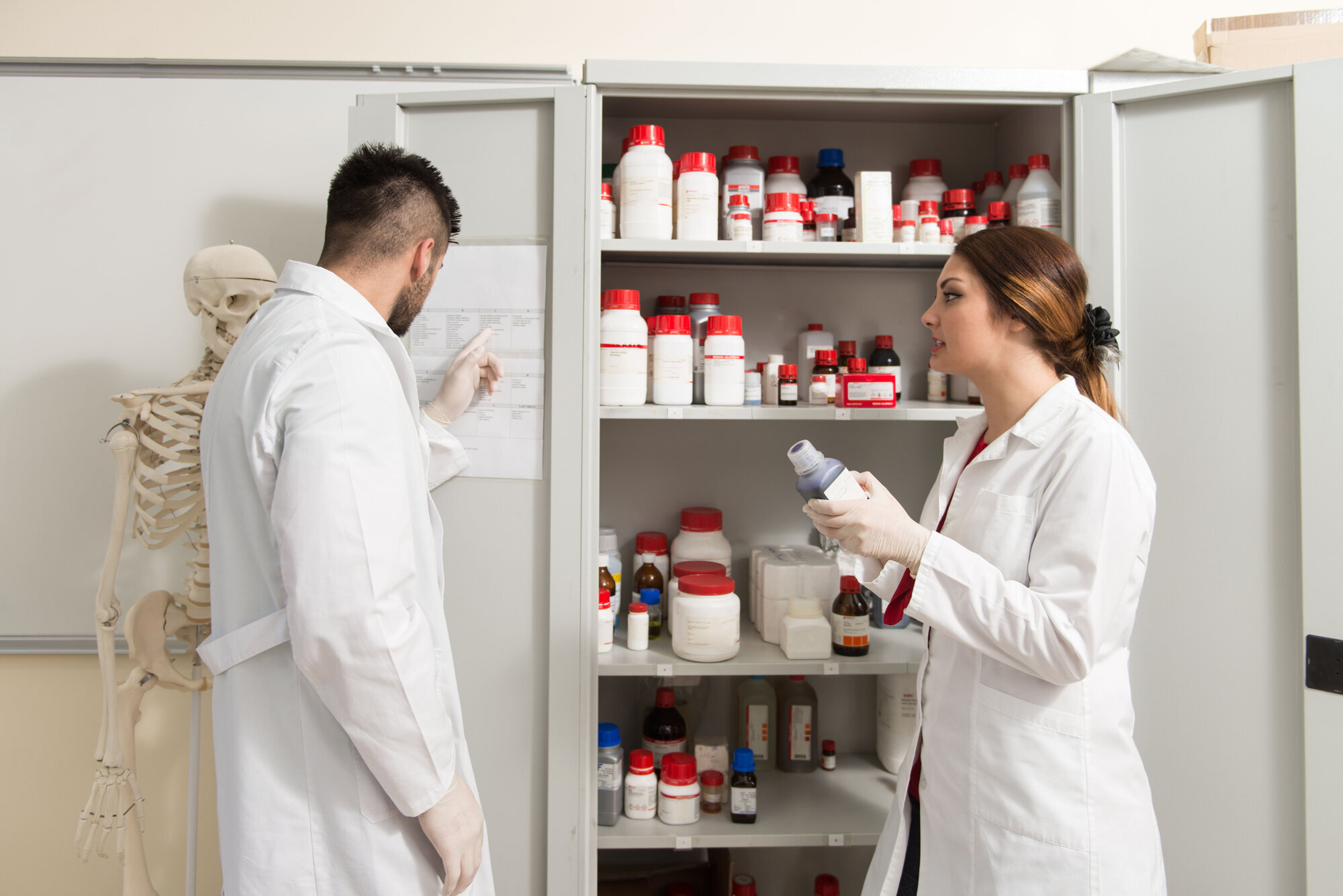 Bilde av to medisinstudenter som kikker inn i et medisinskap