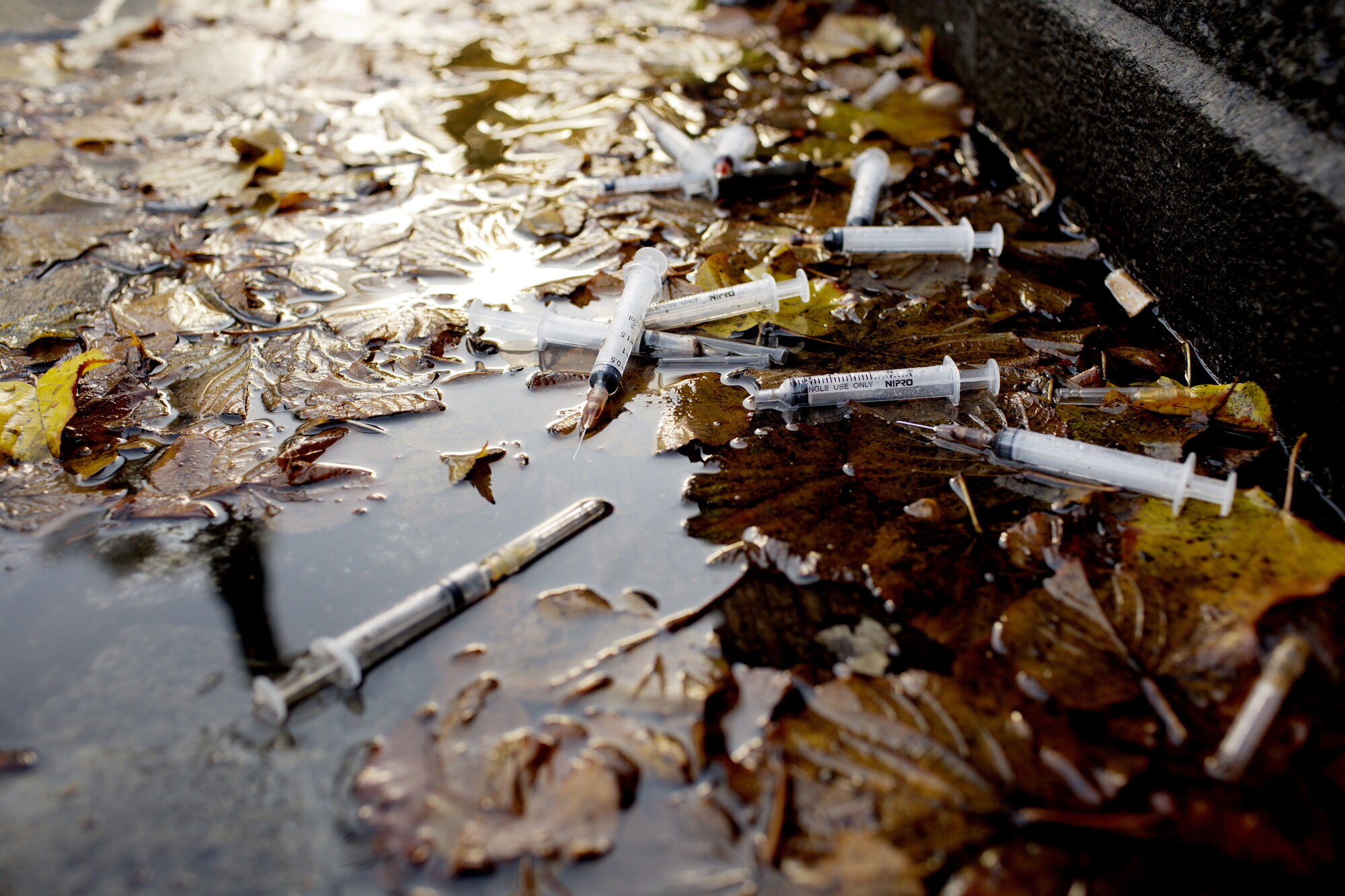 Bildet viser brukte sprøyter i en vannpytt.